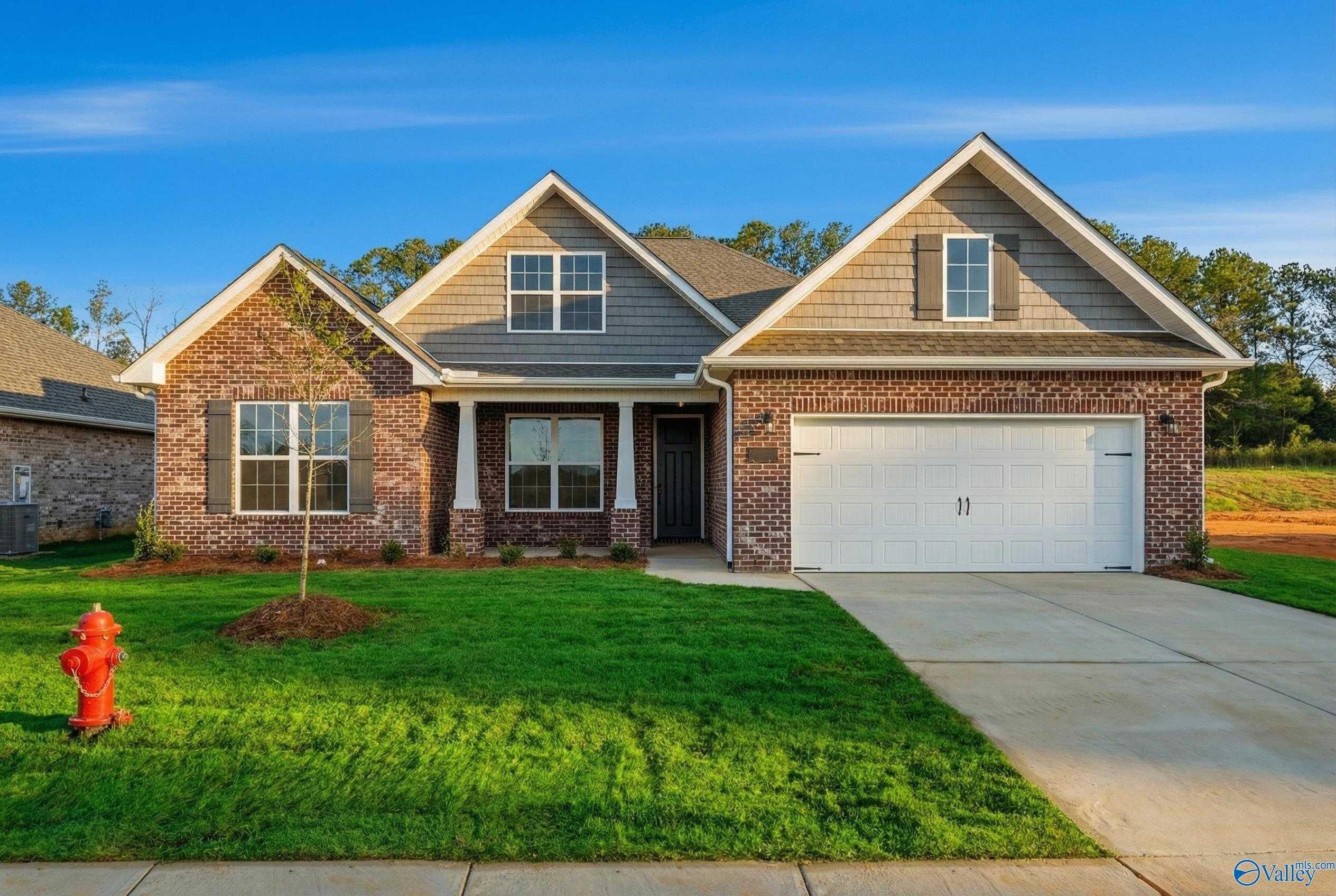 Modern 1-story Rockford B home by Davidson Homes with brick siding, 2-car garage, and lush front yard in Cain Park, Hartselle, Alabama