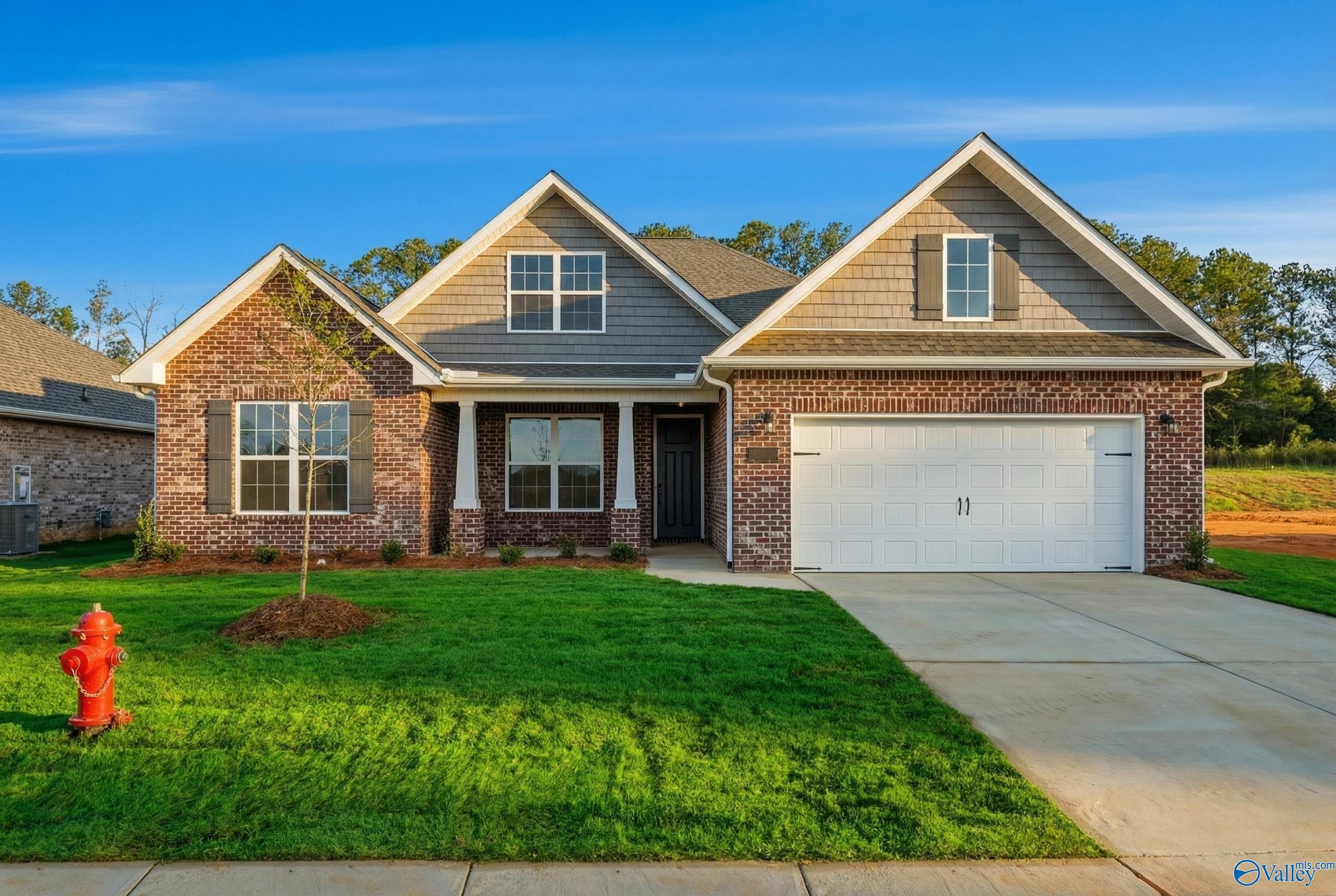 Modern brick single-story home with gabled roof, 2-car garage, front porch, and lush lawn in Cain Park, Hartselle, Alabama