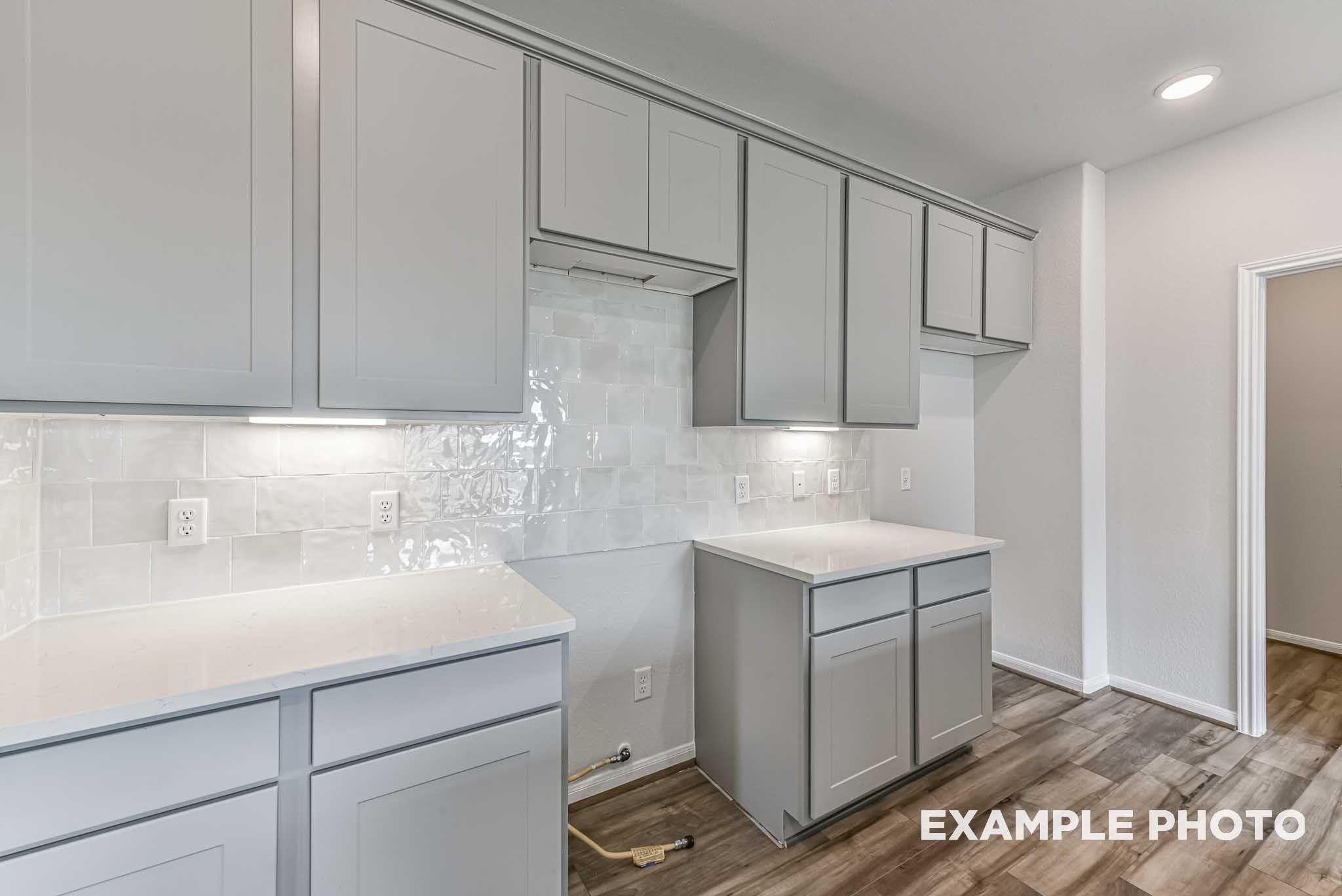 Modern kitchen with gray shaker cabinets, subway tile backsplash, and quartz countertops in Davidson Homes The Costa A, Dayton, Texas
