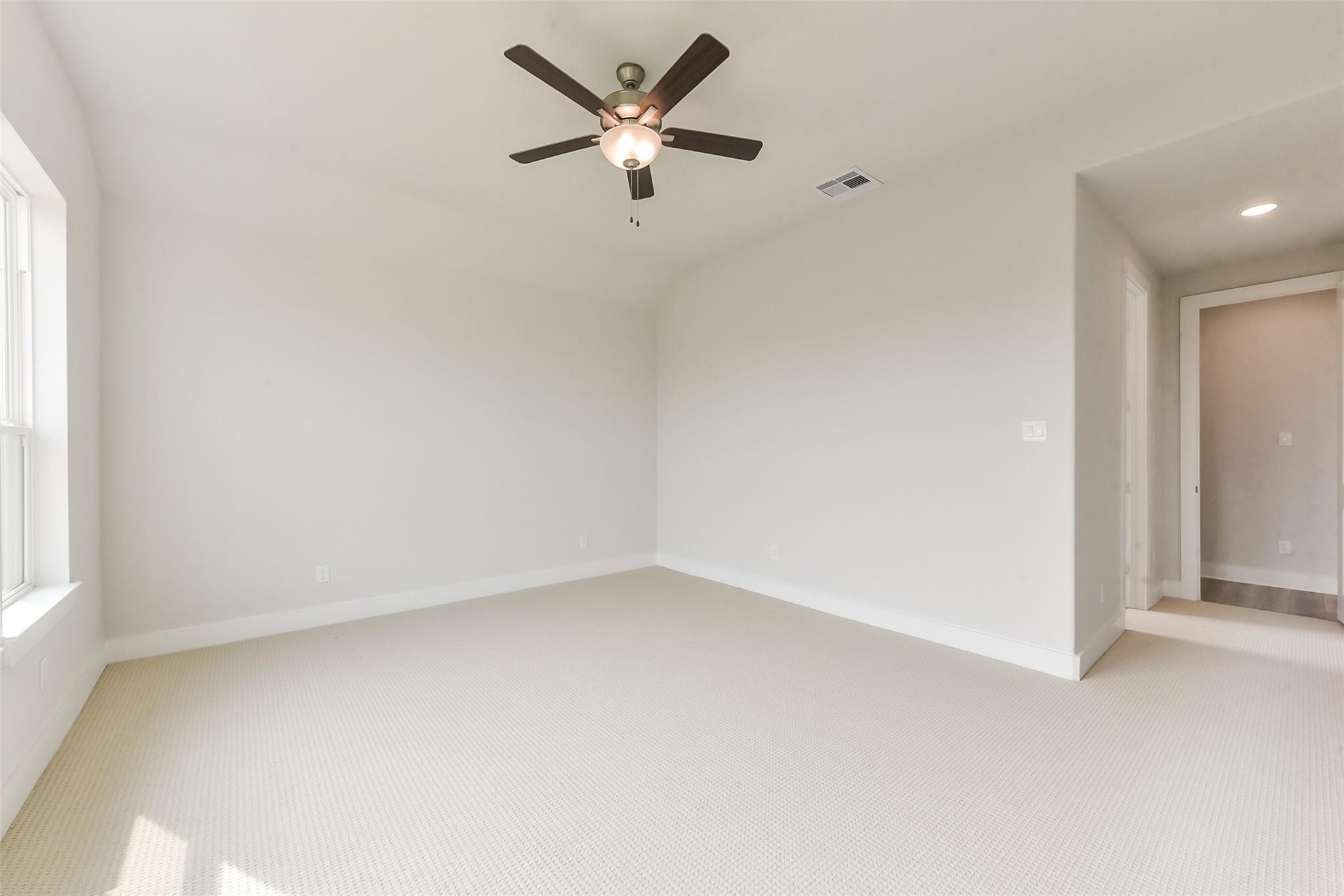 Empty secondary bedroom with ceiling fan, large window, and neutral tones in Davidson Homes The Edward A, Lago Mar, Texas City