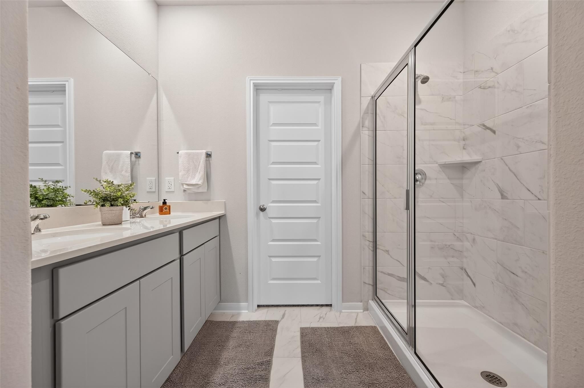 Elegant master bathroom with gray double vanity, frameless glass shower, and subway tile in Davidson Homes The Brazos E, Magnolia, Texas