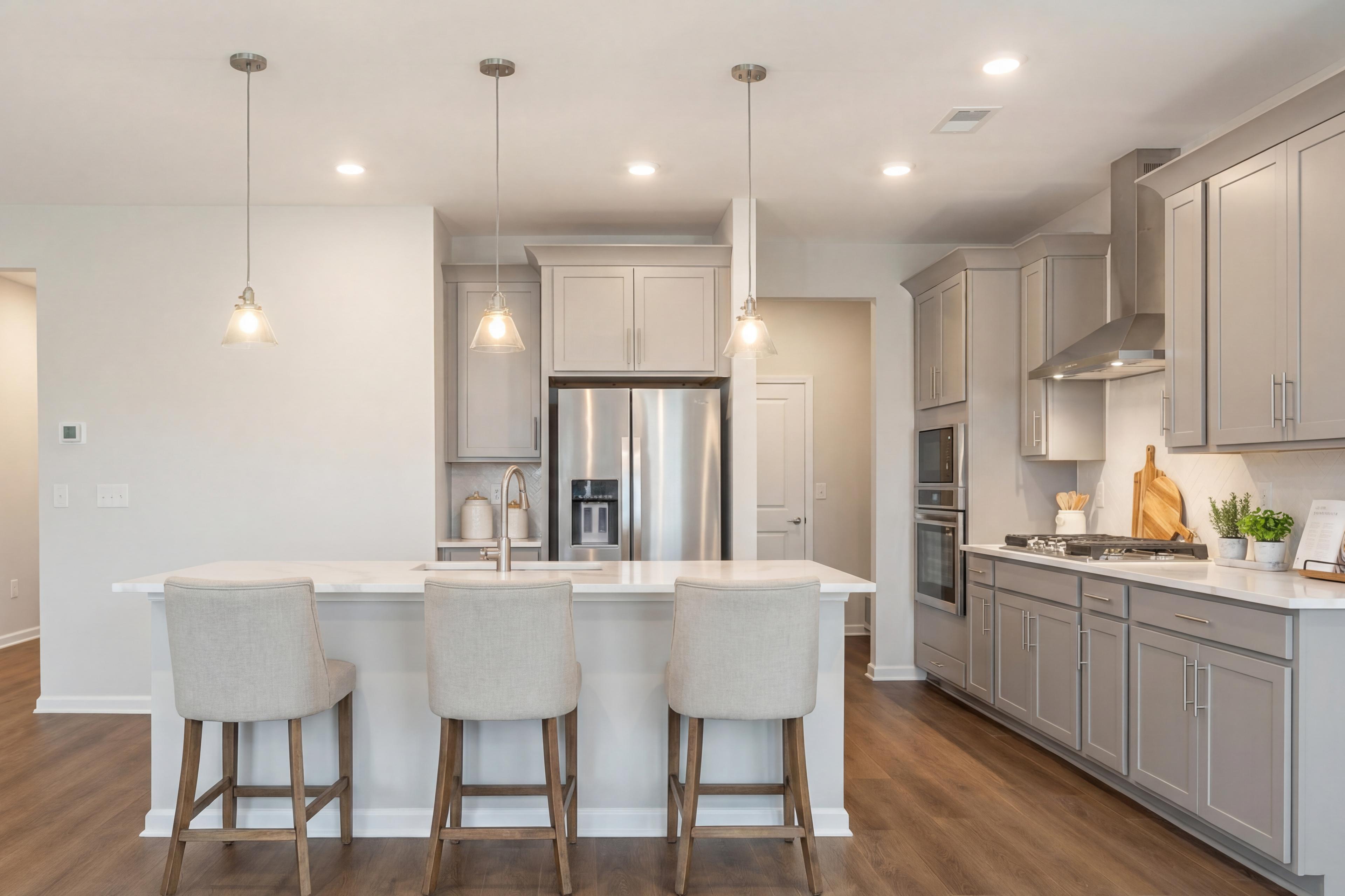 Modern kitchen in Lake Shore Winder GA with white shaker cabinets, large island bar stools, stainless steel appliances, hardwood floors