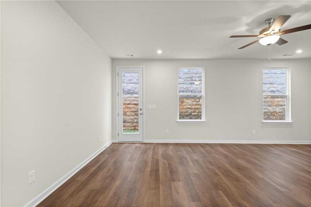 Spacious living room with ceiling fan, French doors, and windows overlooking brick exterior in Davidson Homes The Marion B, Kennesaw, GA