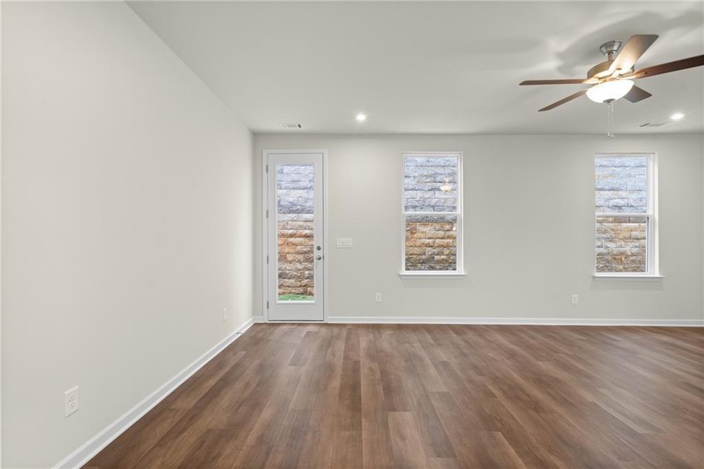 Spacious living room with ceiling fan, French doors, and windows overlooking brick exterior in Davidson Homes The Marion B, Kennesaw, GA
