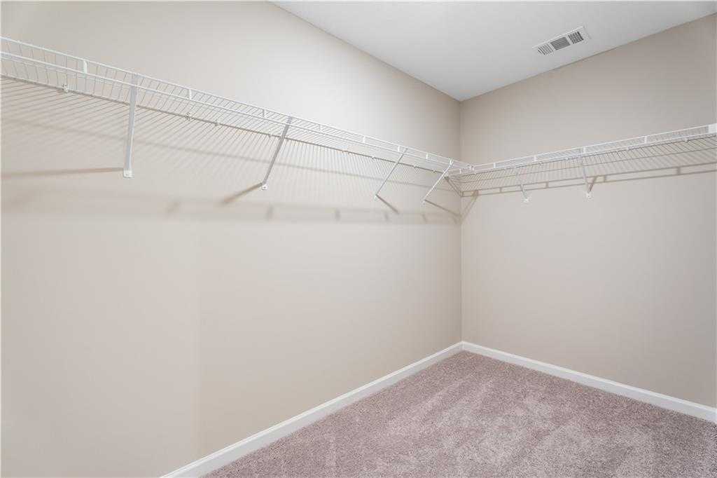 Spacious walk-in closet with white wire shelving on beige walls in master suite, The Bartlett by Davidson Homes, Phenix City, AL