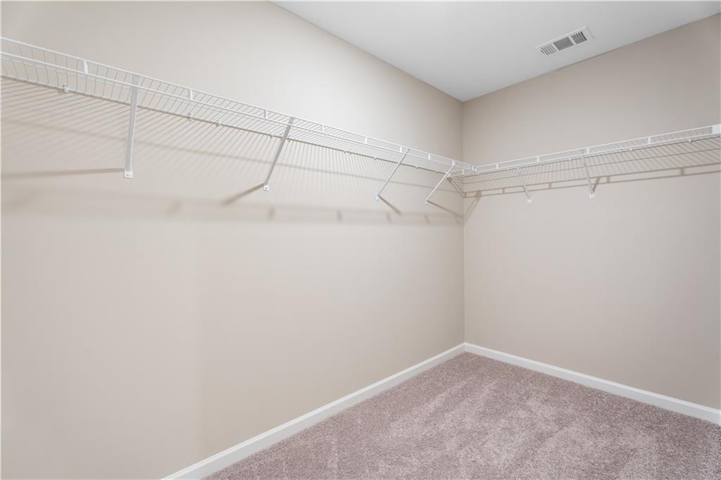 Spacious walk-in closet with white wire shelving on beige walls in master suite, The Bartlett by Davidson Homes, Phenix City, AL