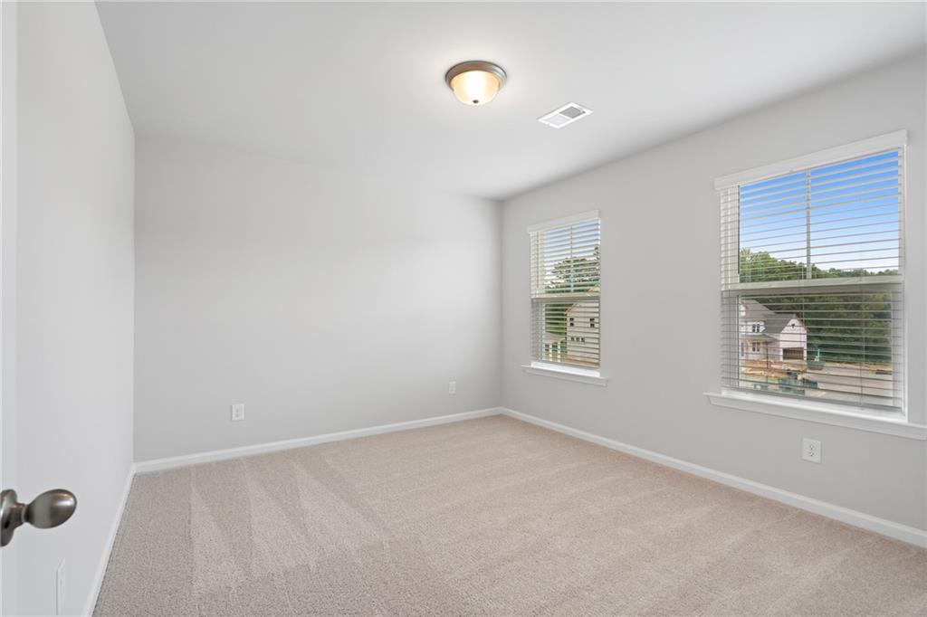 Bright secondary bedroom with beige carpet, large windows, and neutral walls in Davidson Homes The Hickory A, Winder, GA