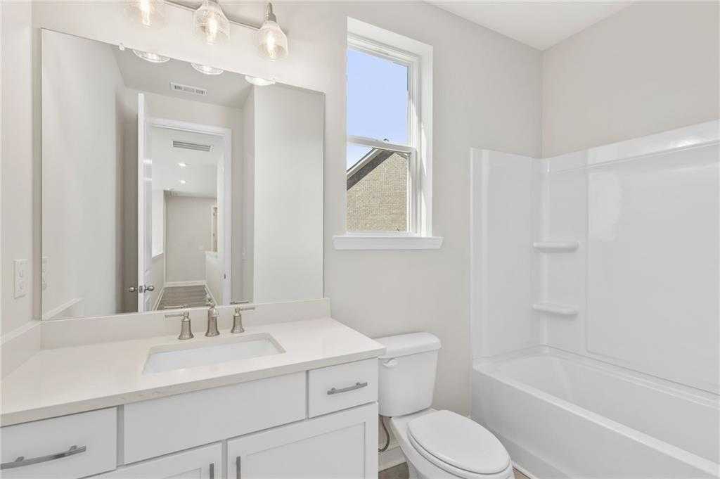 Spacious modern bathroom with white vanity, soaking tub, glass shower, and natural light in Davidson Homes The Danbury C, Buford, Georgia