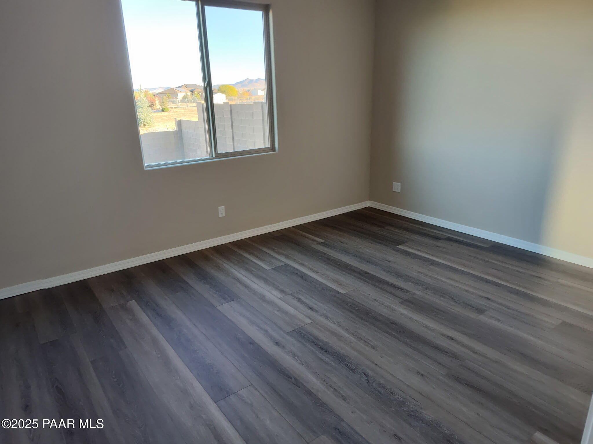 Empty bedroom with luxury vinyl plank flooring and large window overlooking desert mountains in Davidson Homes The Inspiration A, Prescott Valley AZ