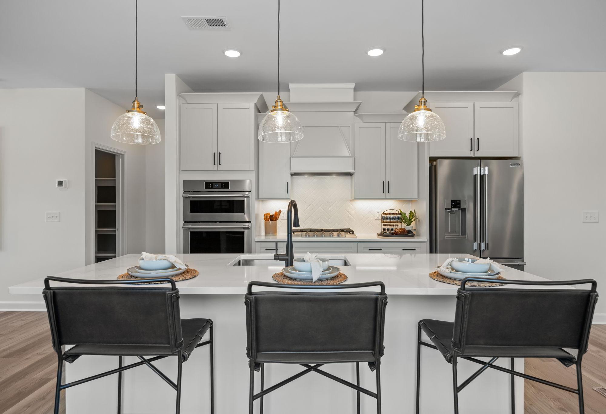 Modern kitchen design in The Mitchell featuring a central island, stainless steel appliances, and stylish pendant lighting.