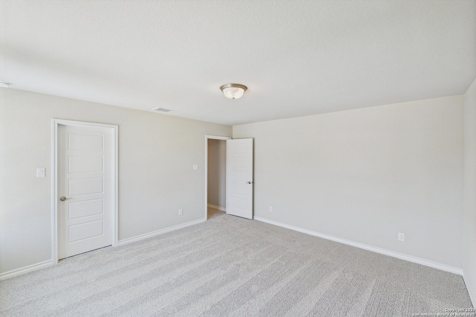Empty secondary bedroom with beige walls, neutral striped carpet, and double doors in Davidson Homes The Jennings H, Ladera, San Antonio