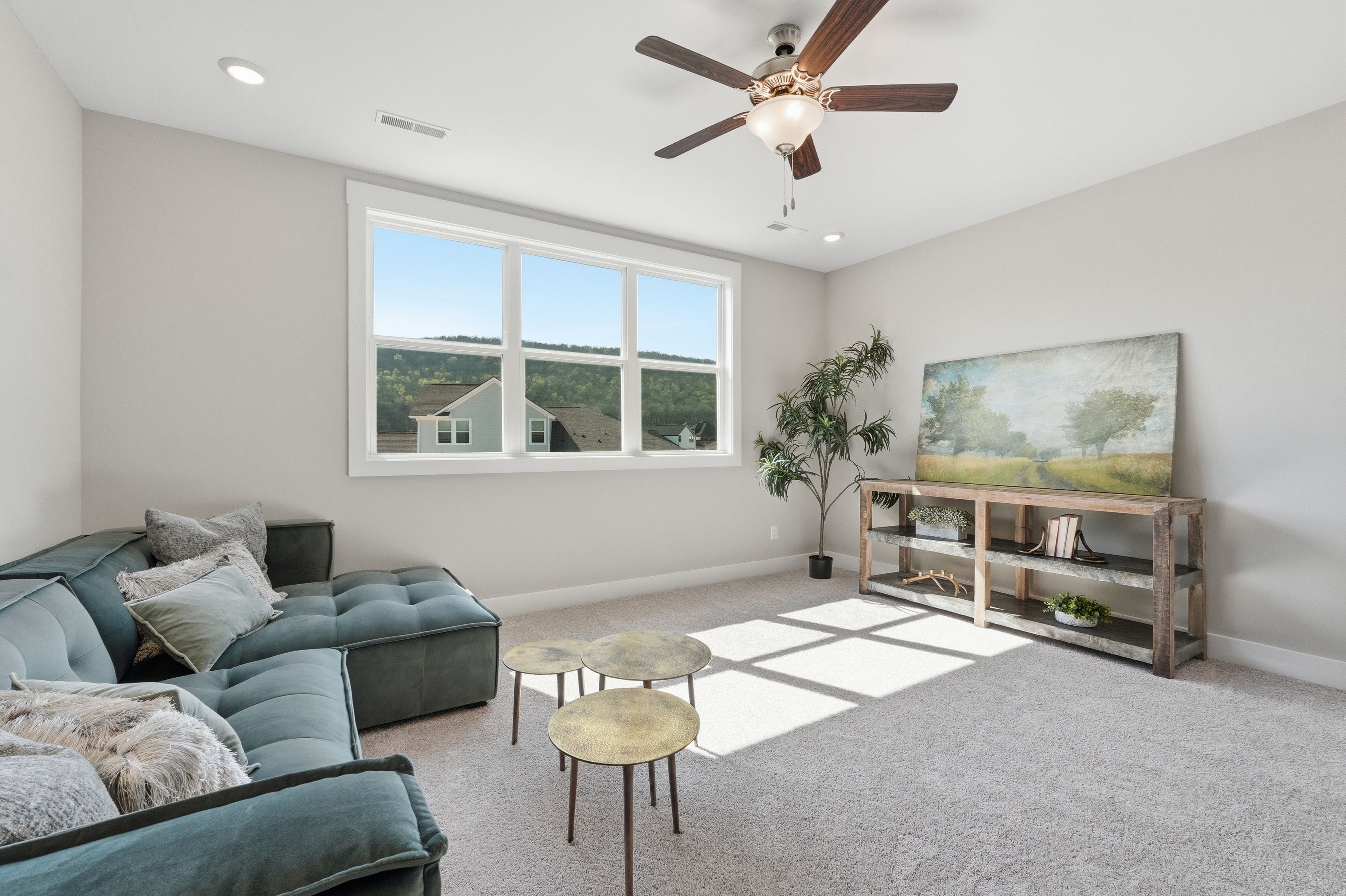 Cozy bonus room at The Meadows at Hampton Cove in Owens Cross Roads AL with L-shaped sectional sofa, media console, and scenic hillside view