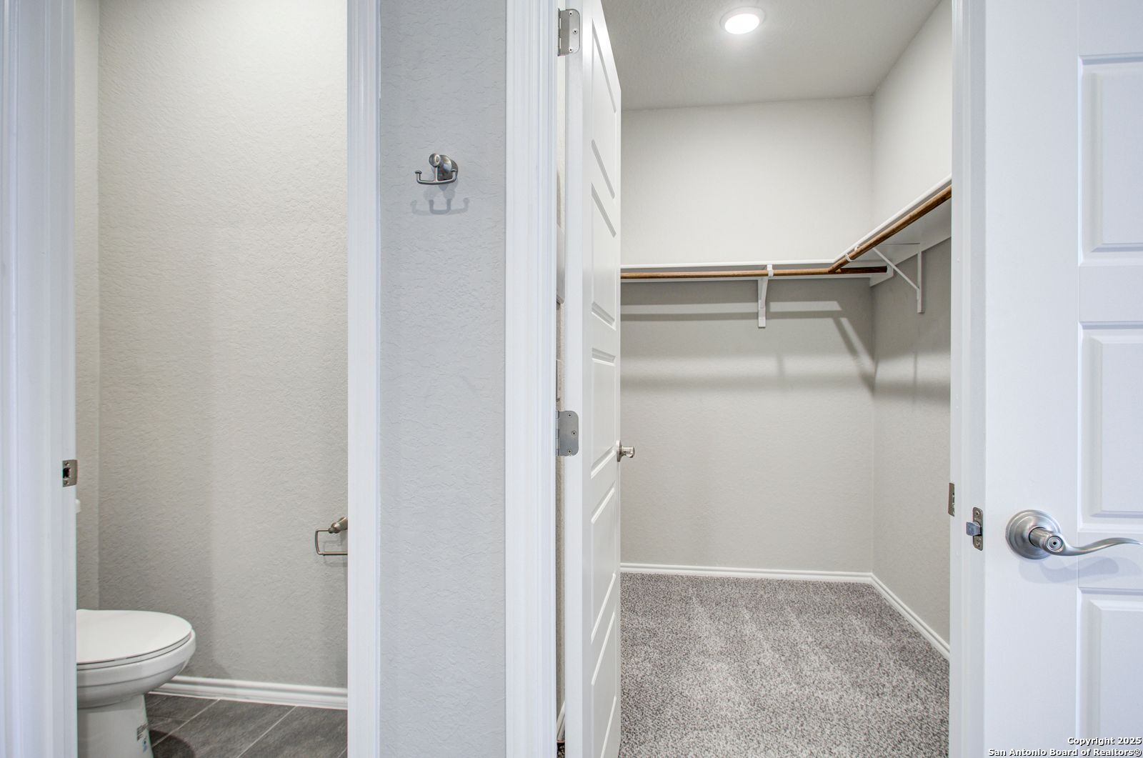 Master bathroom with white toilet and adjacent walk-in closet with shelves in Davidson Homes The Douglas G, San Antonio, Texas