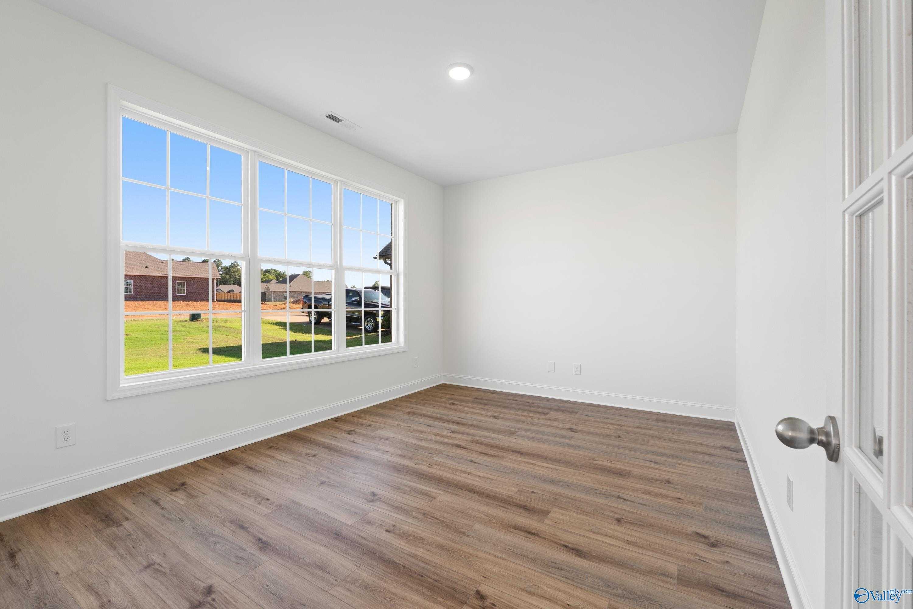 Bright empty bedroom with large windows overlooking green field and neighborhood in Davidson Homes The Oxford, Creekside, Harvest, Alabama