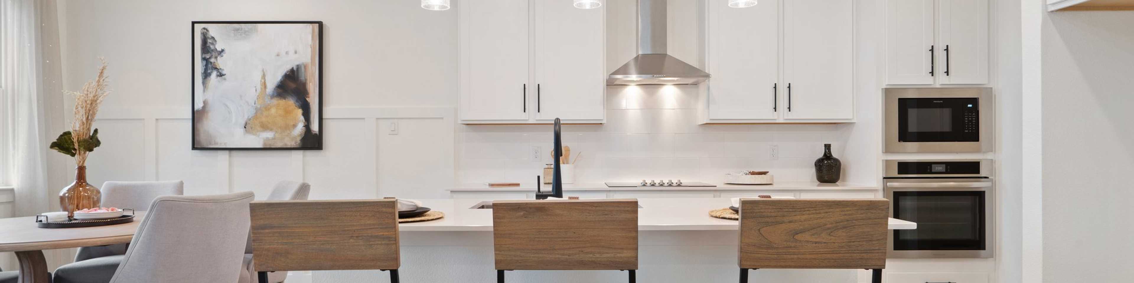 Spacious modern kitchen with white cabinets, island bar stools, pendant lights at Lake Park Villas in Wylie Texas