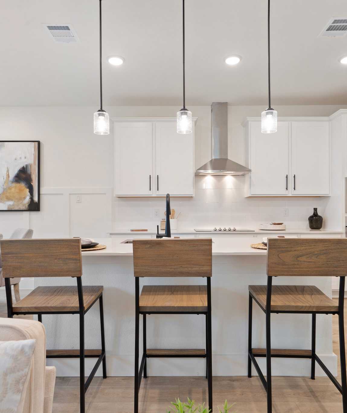 Spacious modern kitchen with white cabinets, island bar stools, pendant lights at Lake Park Villas in Wylie Texas