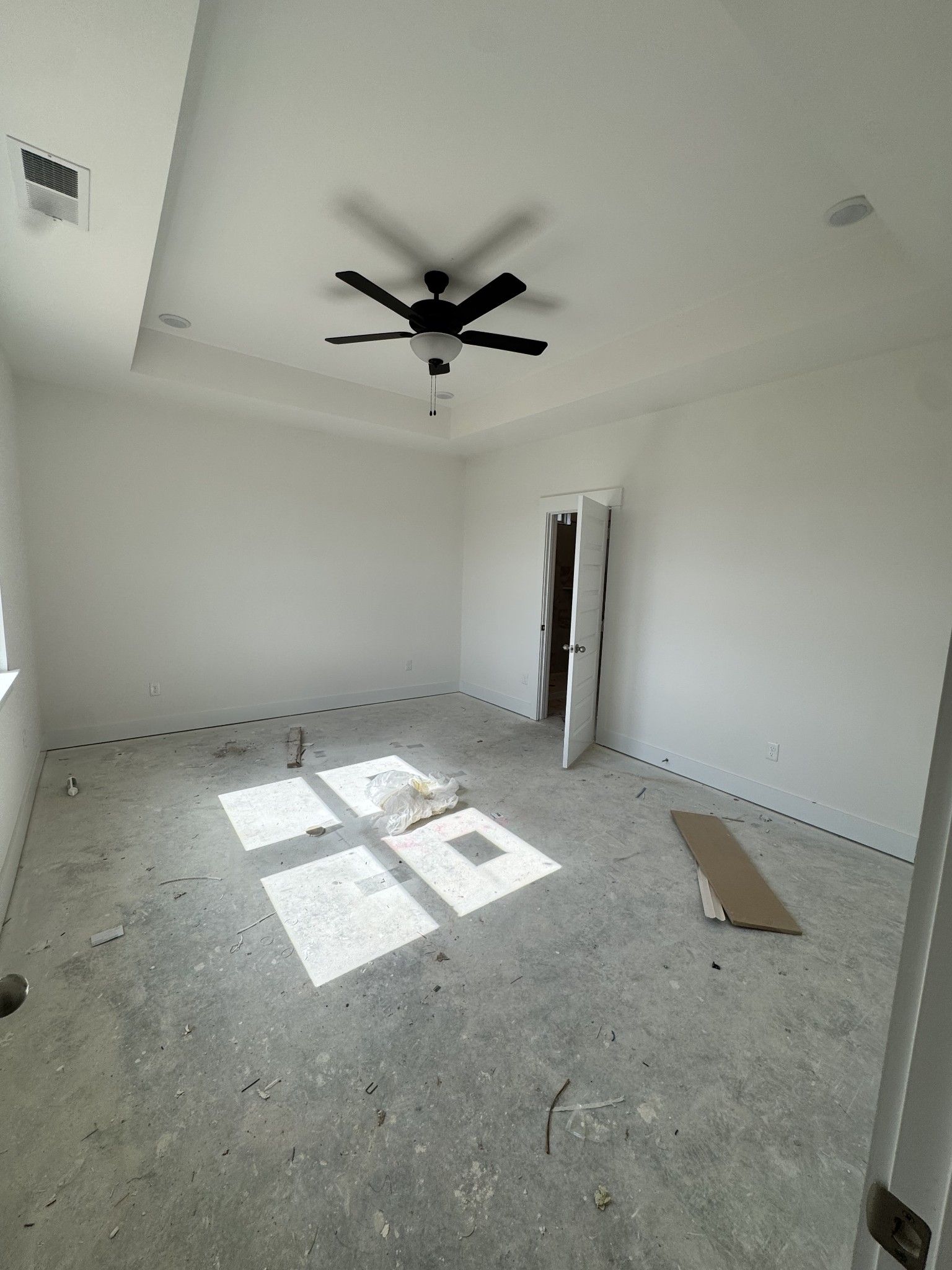 Unfinished bedroom with white walls, ceiling fan, open door, and sunlight through windows in Davidson Homes Prairie C, Gallatin, TN