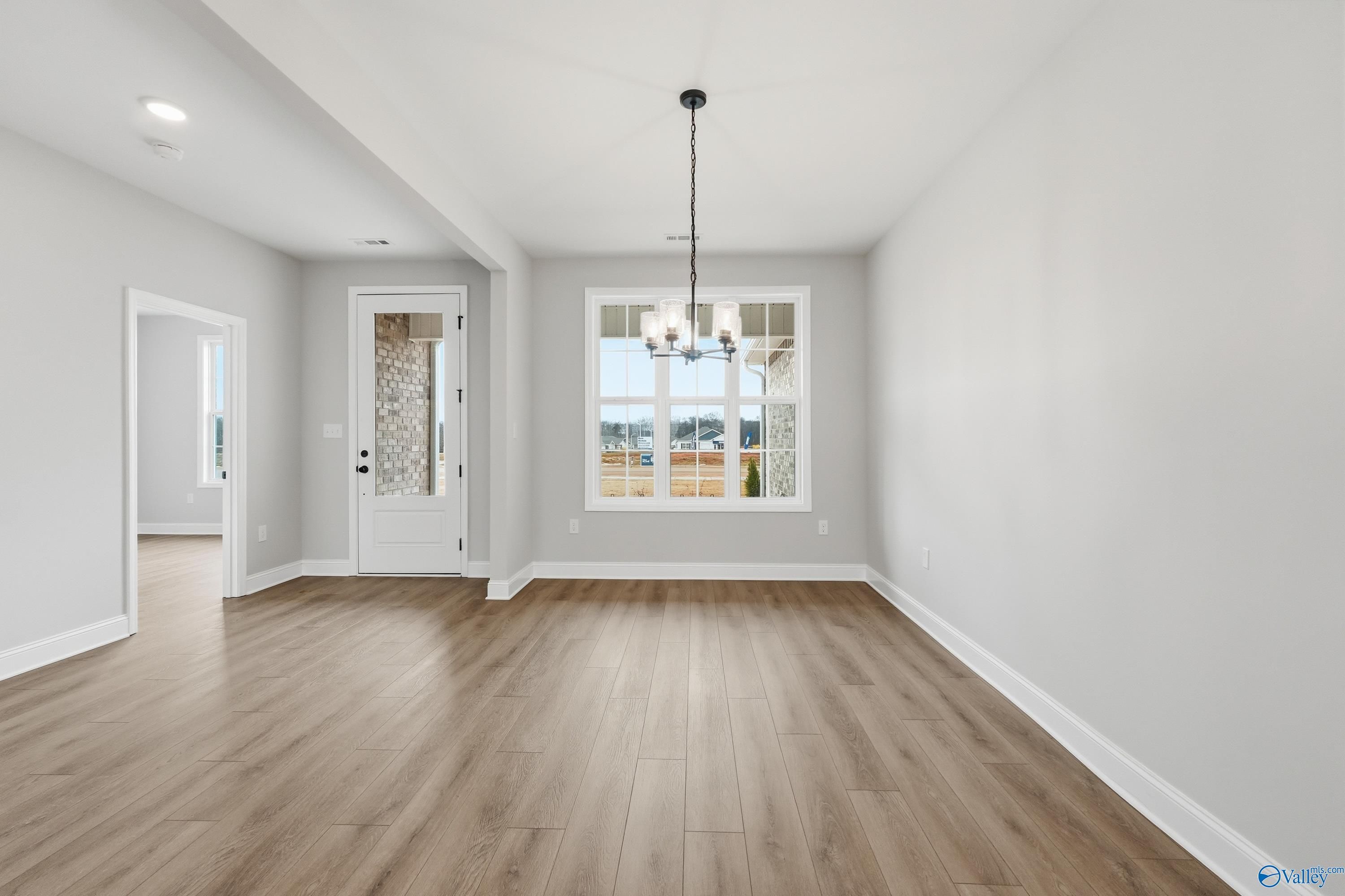 Spacious dining room with hardwood floors, gray walls, chandelier, and large window in Davidson Homes The Finleigh, Meridianville, AL