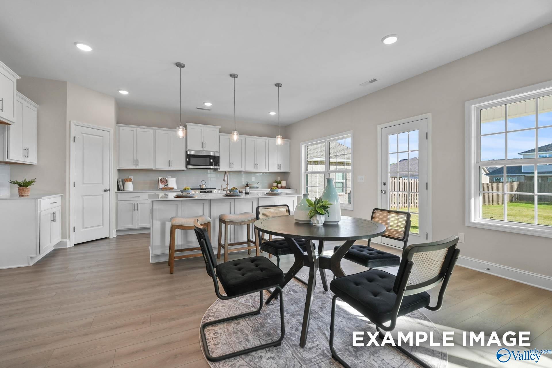 Bright dining nook with round black table, wicker chairs, white cabinets, and backyard views in Davidson Homes Madison A, Harvest AL