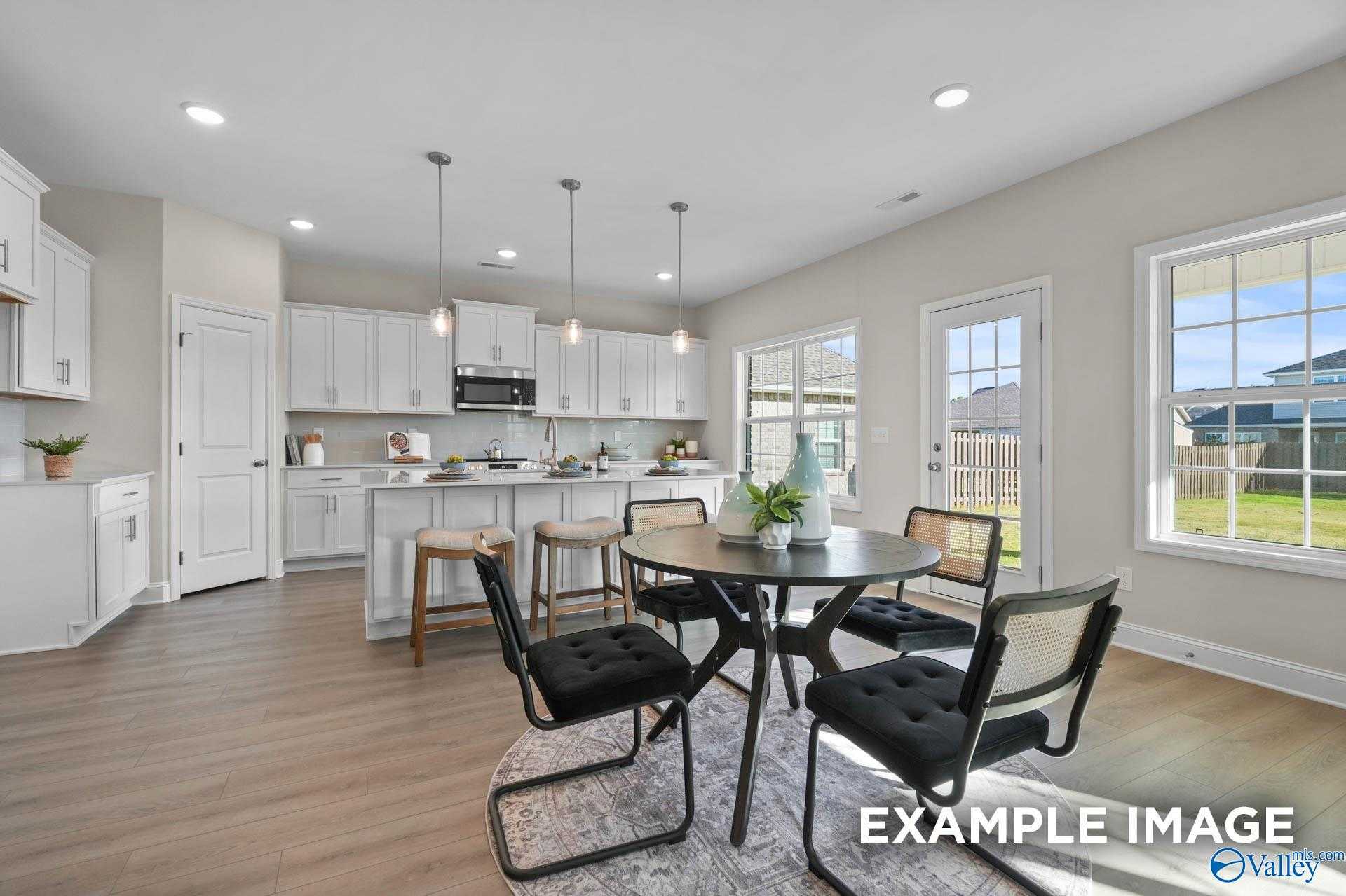 Bright dining nook with round black table, wicker chairs, white cabinets, and backyard views in Davidson Homes Madison A, Harvest AL