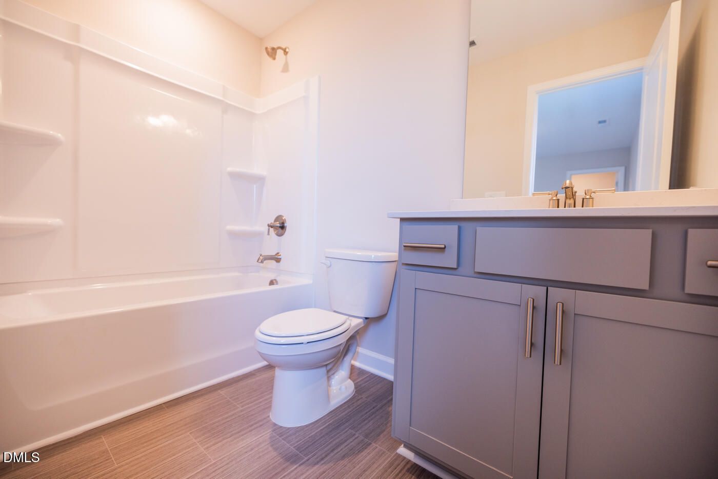 Modern bathroom with bathtub-shower combo, gray vanity, and toilet in 4-bedroom Hickory II C home, Woodland Crossing, Zebulon, NC