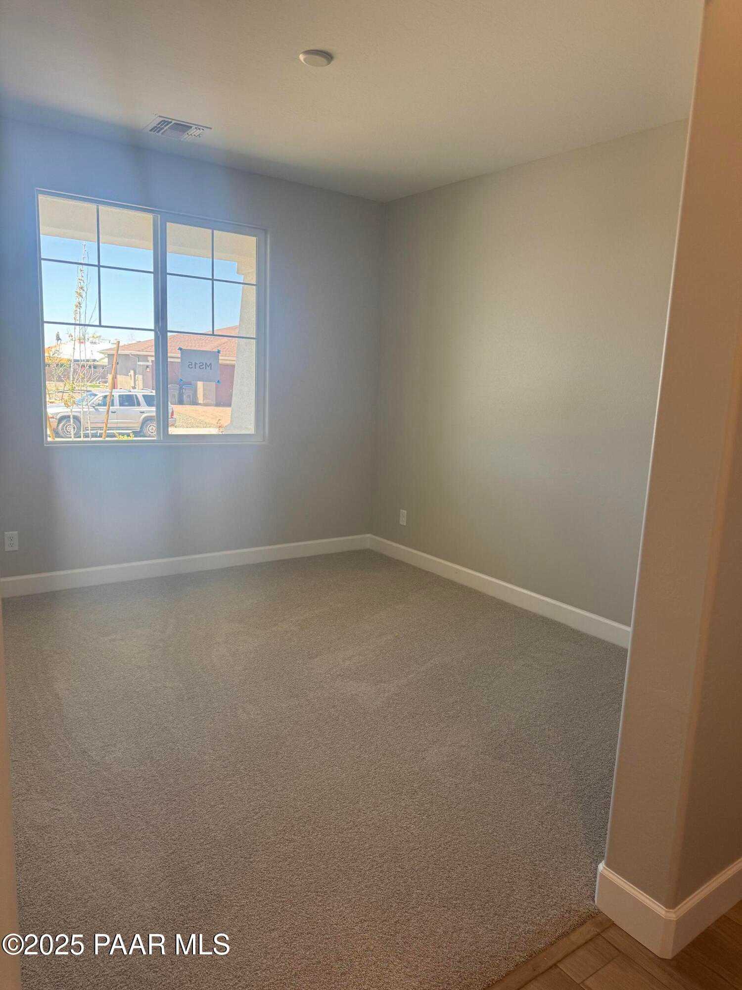 Bright empty bedroom with large sunny window, gray walls, and carpet floor in The Summit B, Evermore Homes, Prescott Valley, AZ