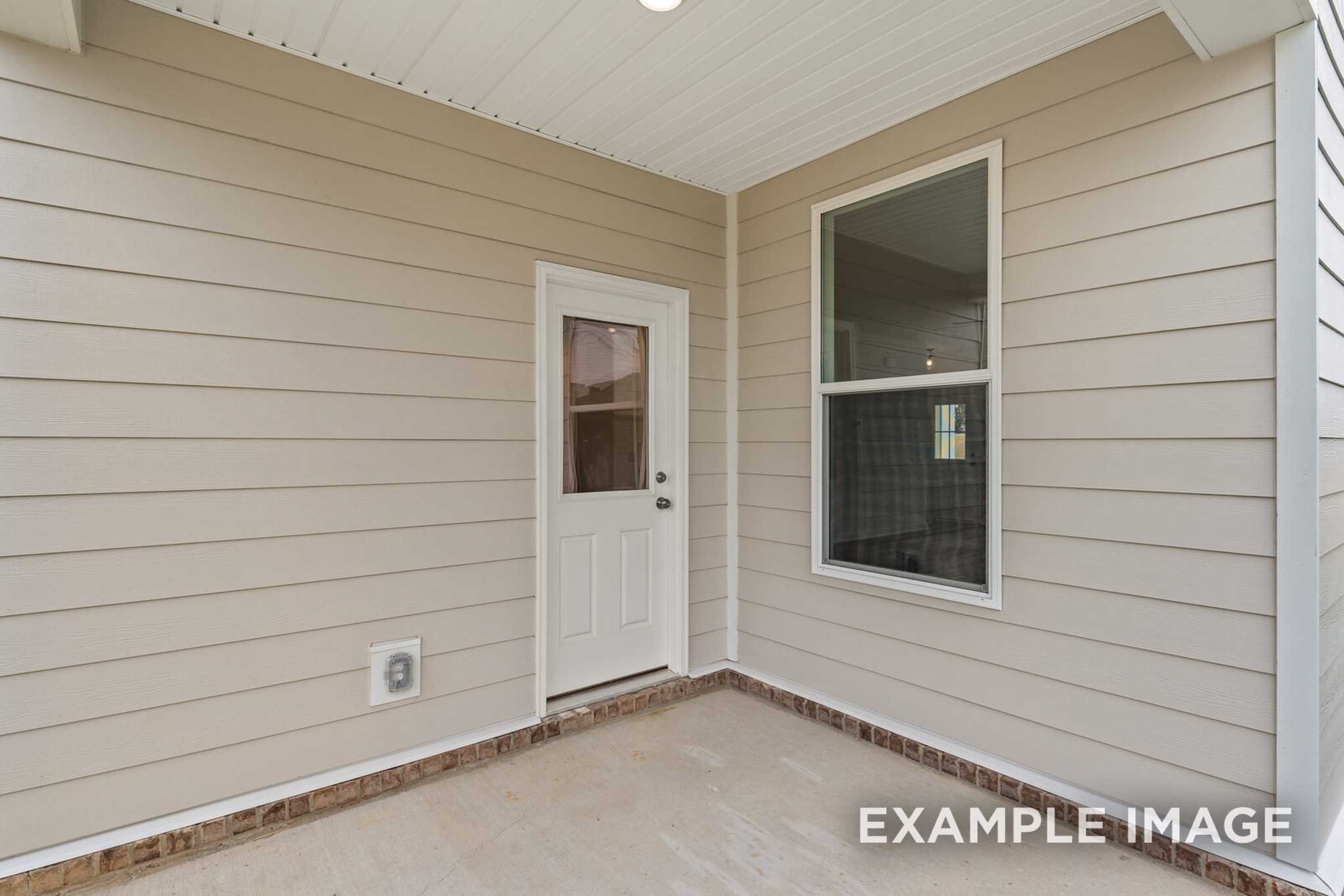 Covered porch entrance of The Murray A Davidson Homes design featuring beige siding, white glass door, and tile flooring