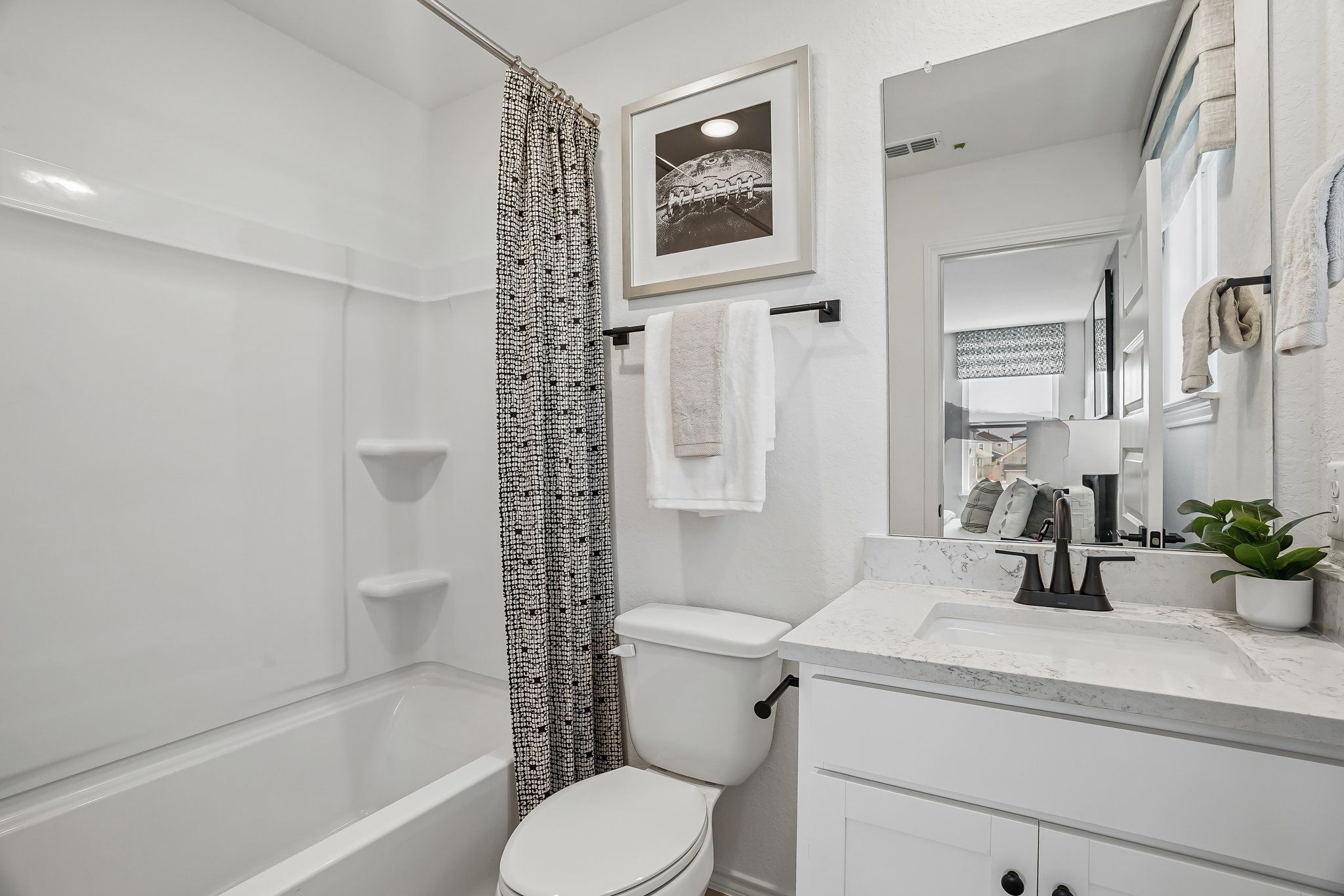 Modern bathroom at Fairway Crossing in Converse, TX featuring white vanity, marble countertop, and shower-tub combination.