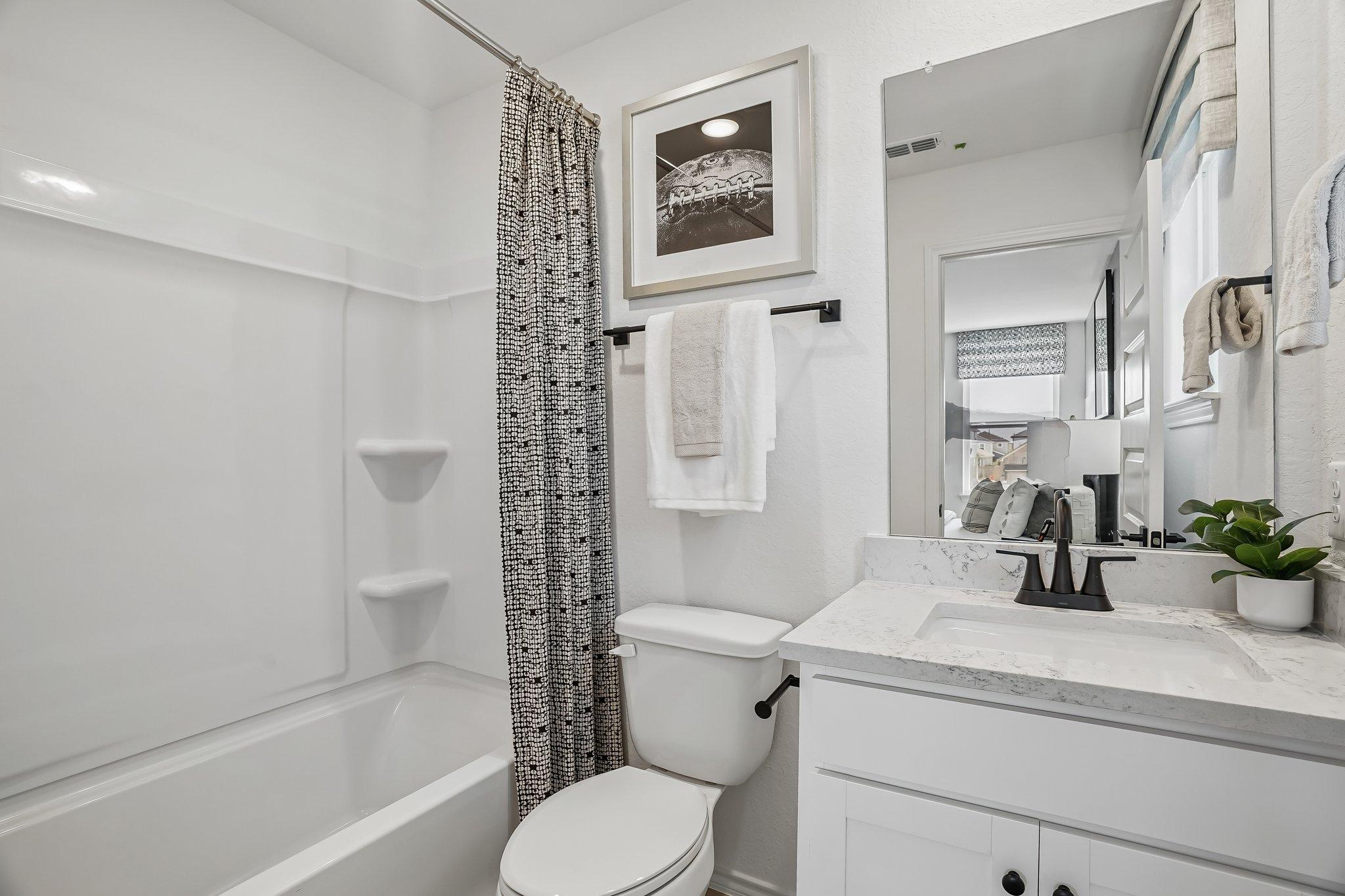 Modern bathroom at Fairway Crossing in Converse, TX featuring white vanity, marble countertop, and shower-tub combination.