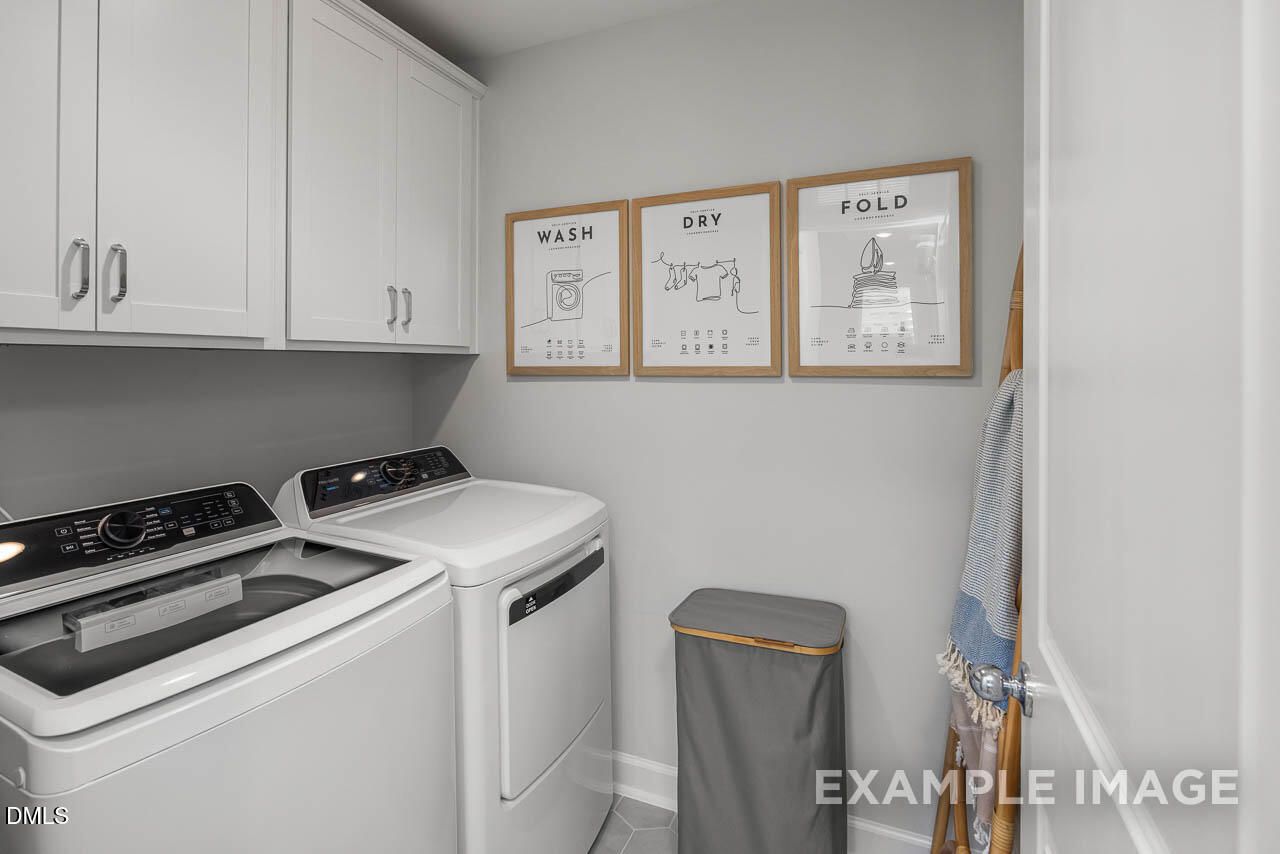 Functional laundry room with white washer, dryer, cabinets, and "Wash Dry Fold" wall art in Davidson Homes The Graham plan, Fuquay-Varina, NC