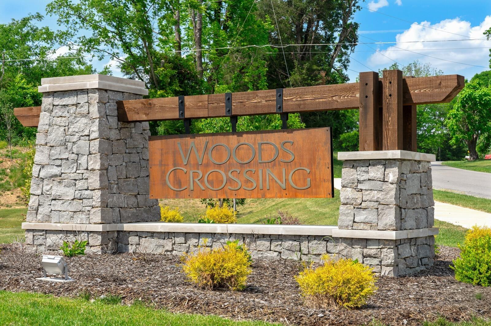 Stone and timber entrance sign for Woods Crossing community in Gallatin, Tennessee by Davidson Homes.