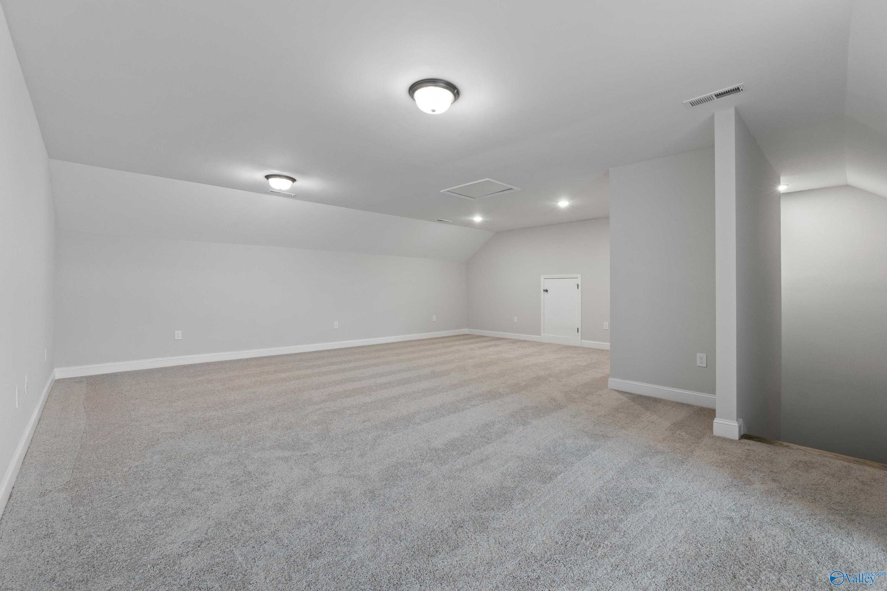 Spacious bonus room with gray carpet, white walls, recessed lighting, and stairs in Davidson Homes The Rockford B with Bonus, Toney, Alabama