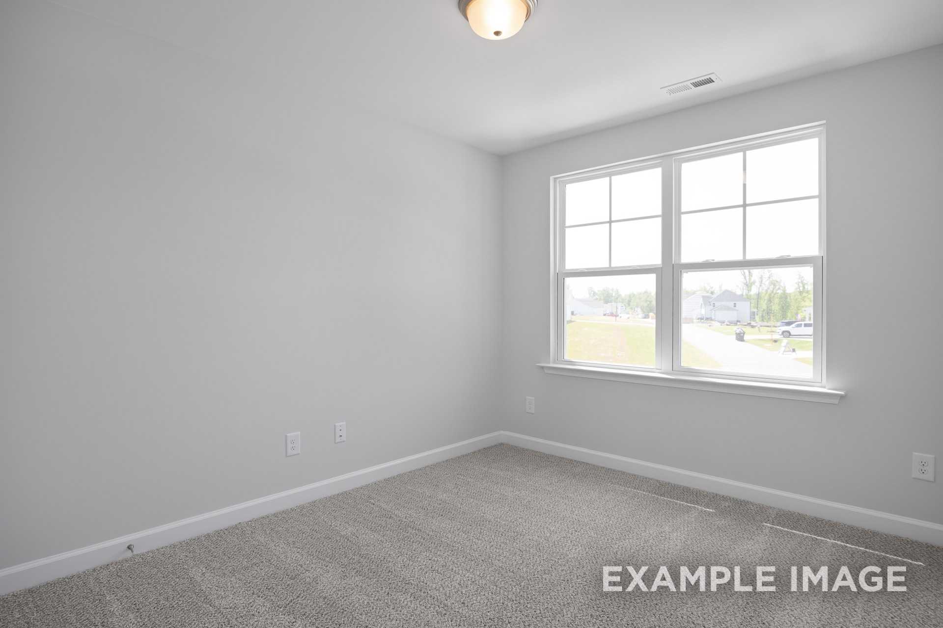 Spacious upstairs bedroom in The Grace C featuring light gray walls, beige carpet, and large window with lawn view