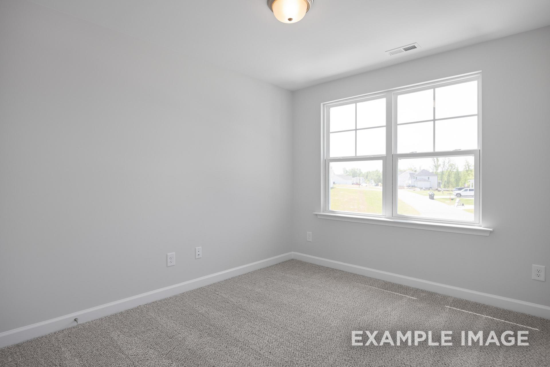 Spacious upstairs bedroom in The Grace C featuring light gray walls, beige carpet, and large window with lawn view