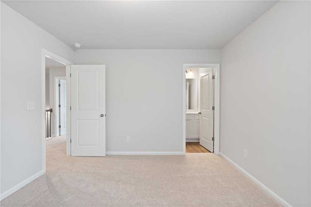 Spacious upstairs bedroom with en-suite bathroom and carpet flooring in Davidson Homes Hickory B, Winder, Georgia