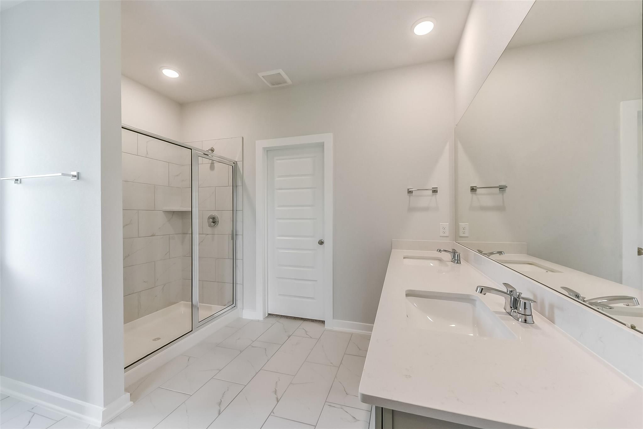Elegant master bathroom with double quartz vanity, frameless mirror, walk-in glass shower in Davidson Homes The Tierra C, Dayton TX