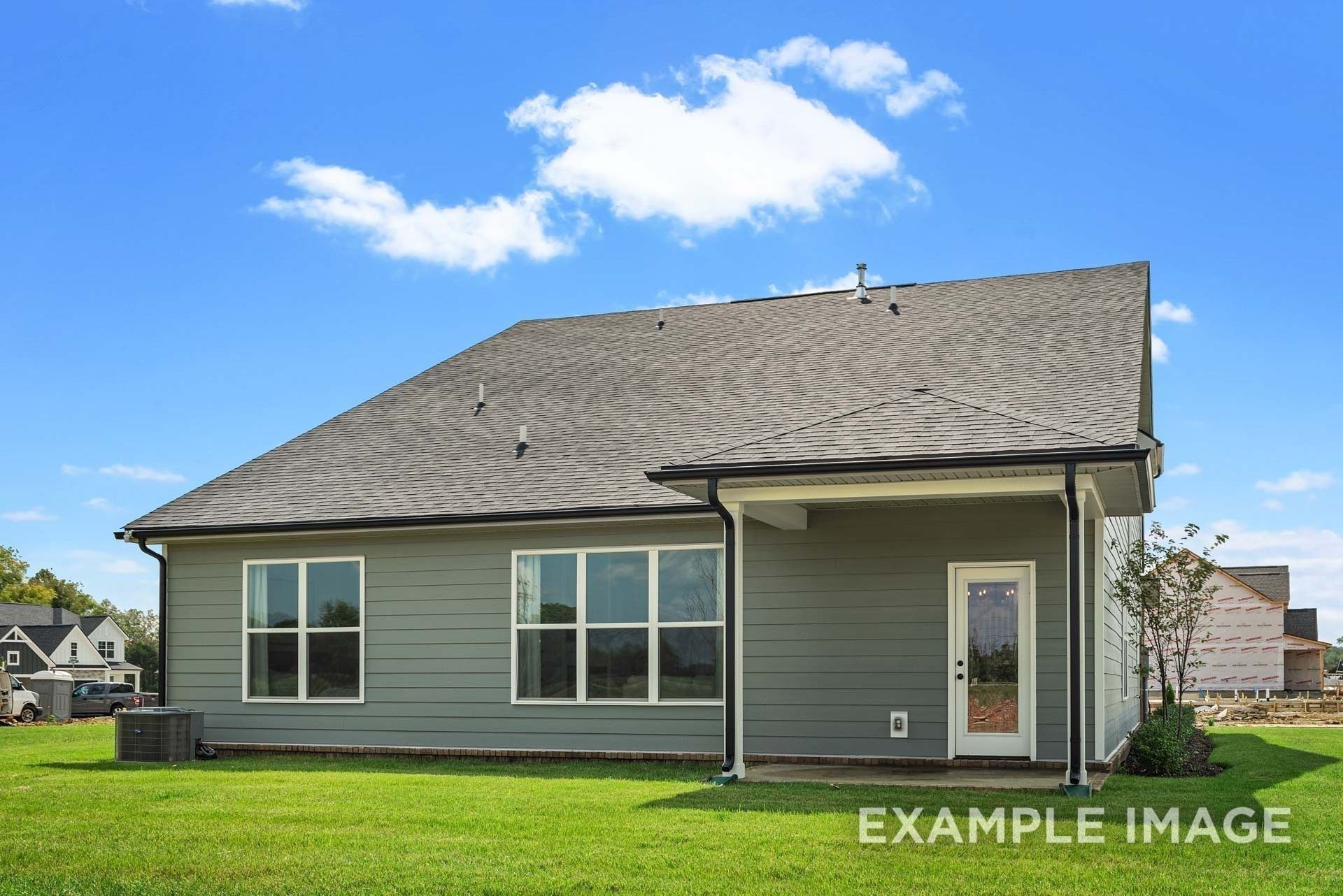 Gray two-story home with shingled roof, large windows, covered patio, and white door in Woods Crossing, Gallatin, Tennessee