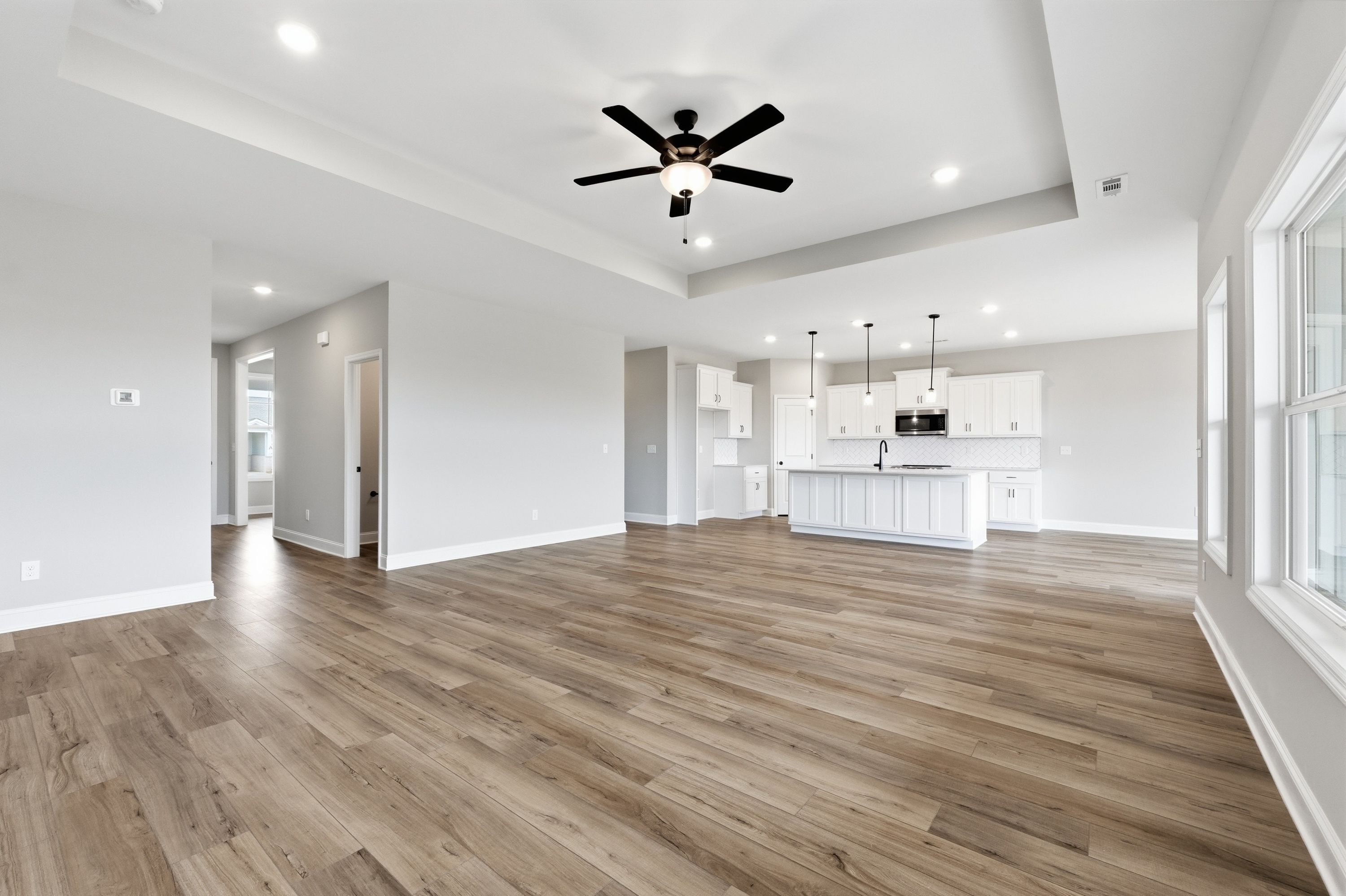 Spacious open-concept kitchen and living area in The Rockford home with hardwood floors, white island, and ceiling fan