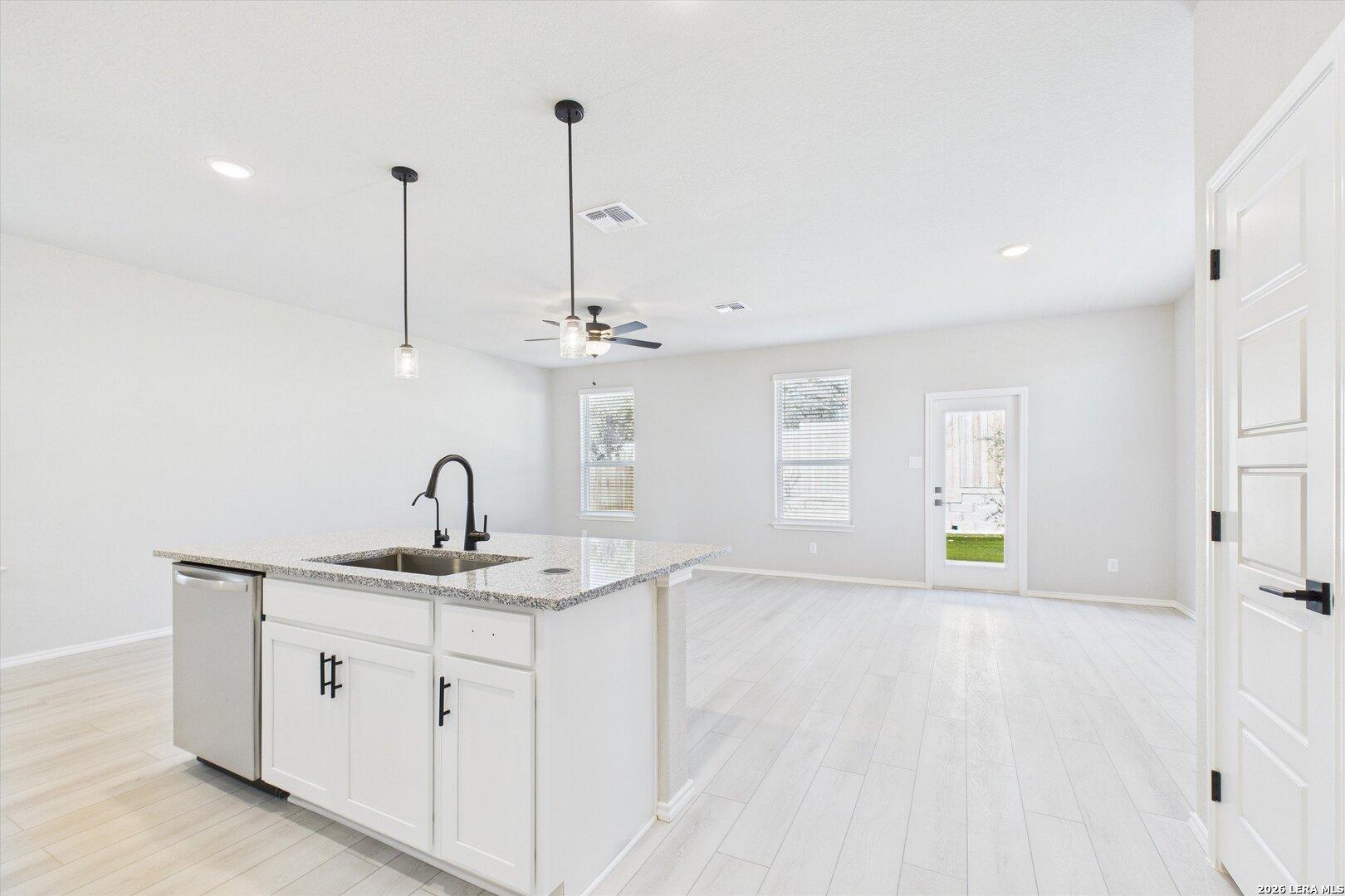 Modern open-concept kitchen with white island, quartz counters, and pendant lights in Davidson Homes The Charlotte A, San Antonio