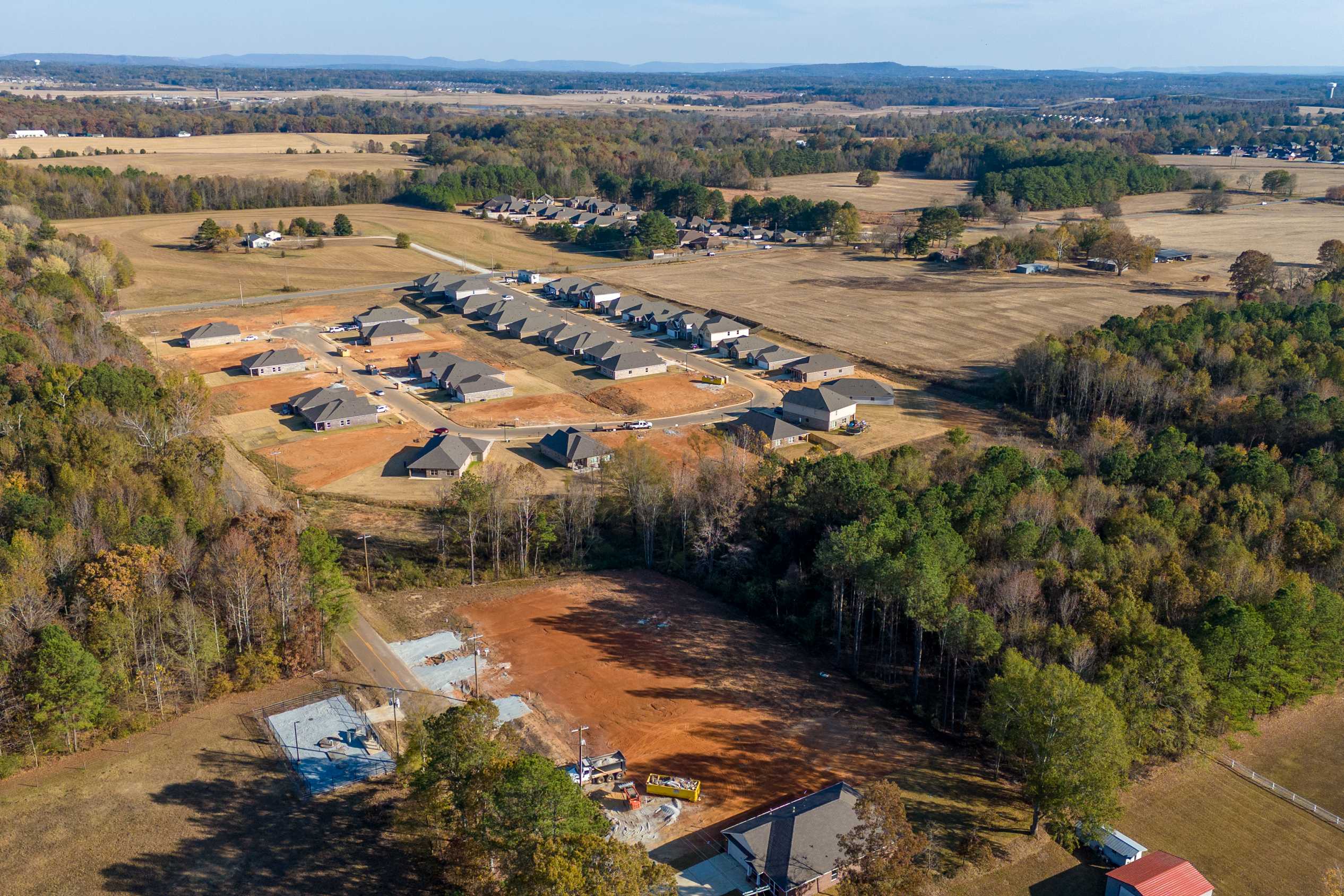 Aerial view of new home construction at Mallard Landing in Athens Alabama by Davidson Homes amid woods fields and red clay soil
