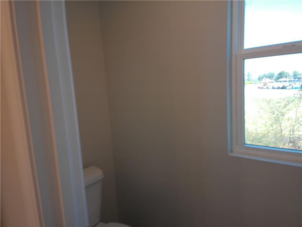 Modern half bath with white toilet, neutral walls, and sunny window view in Davidson Homes The Marion C, Winder, GA