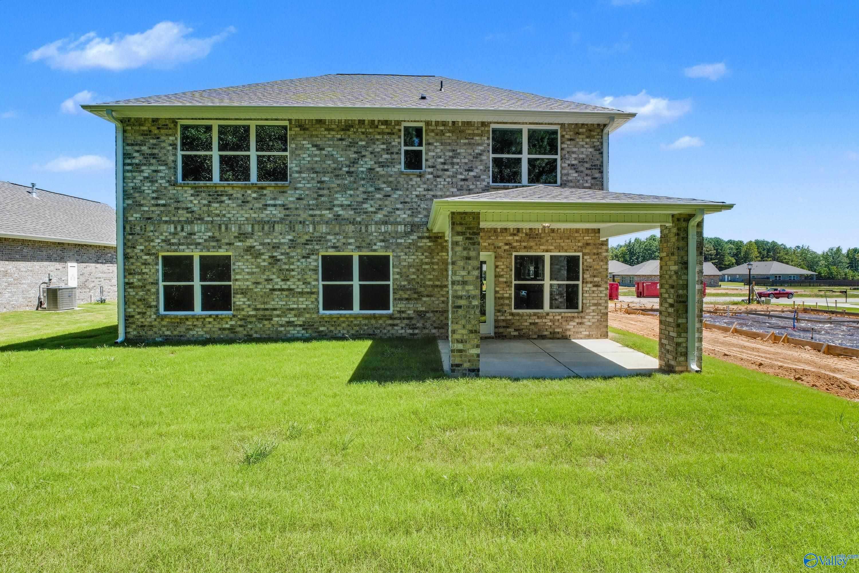Two-story brick home with covered back patio, large windows, and green lawn in The Highlands, Arab, Alabama – The Shelby A by Davidson Homes