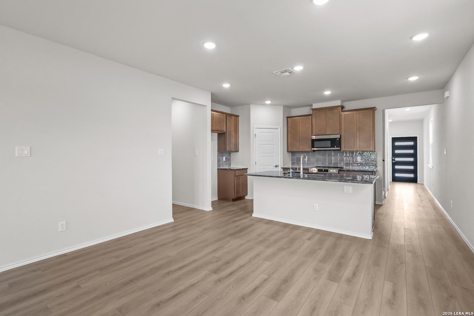 Open-concept kitchen with wood cabinets and granite island in The San Marcos F floor plan, Rayburn Valley, San Antonio.