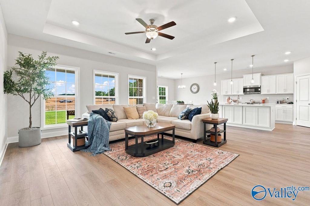 Bright open-concept living room with tray ceiling and white kitchen in The Harrison floor plan by Davidson Homes, Hartselle, Alabama