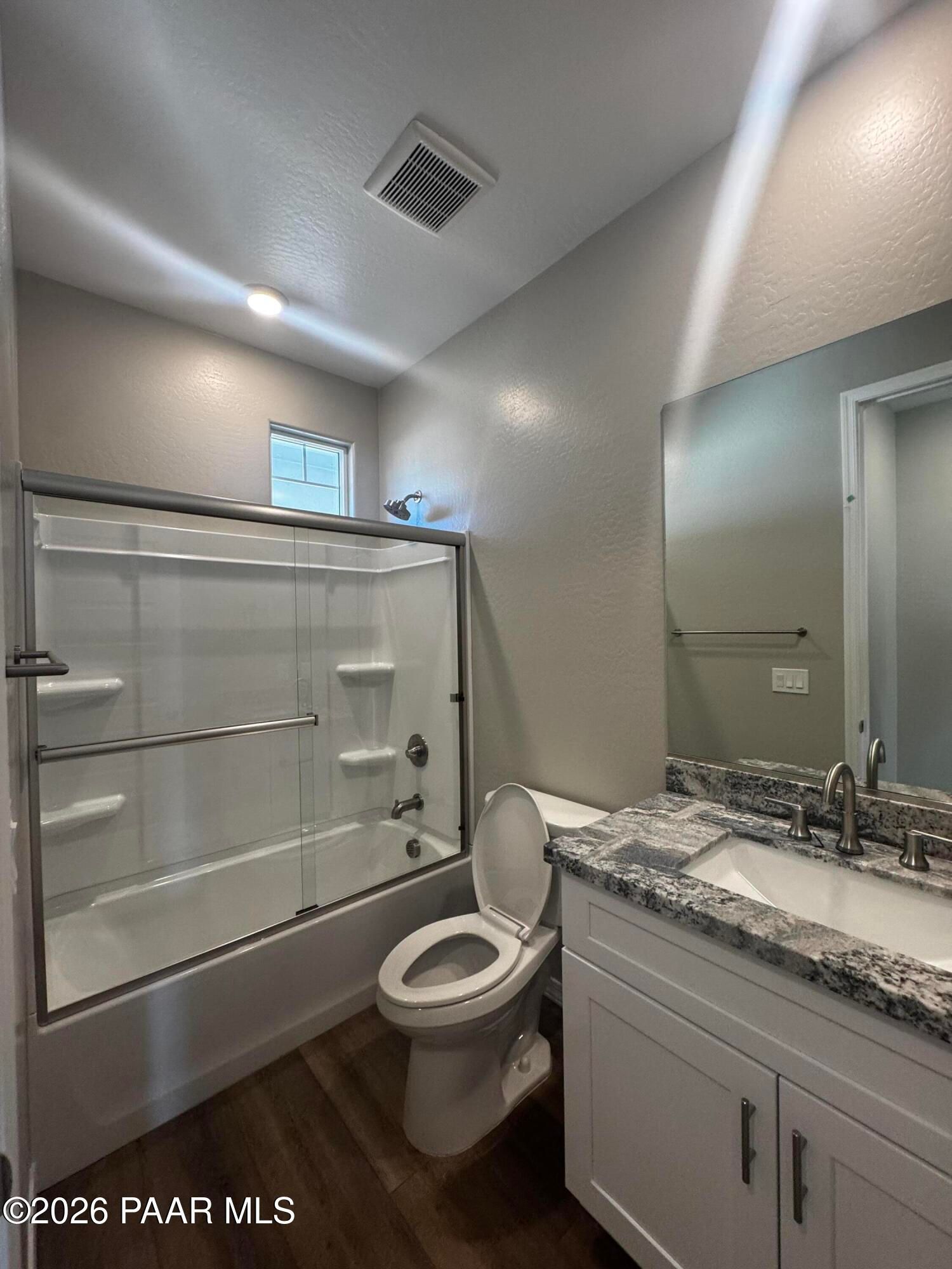 Modern master bathroom featuring glass shower-tub combo, double granite vanity, and wood floors in Davidson Homes Daybreak B, Prescott AZ