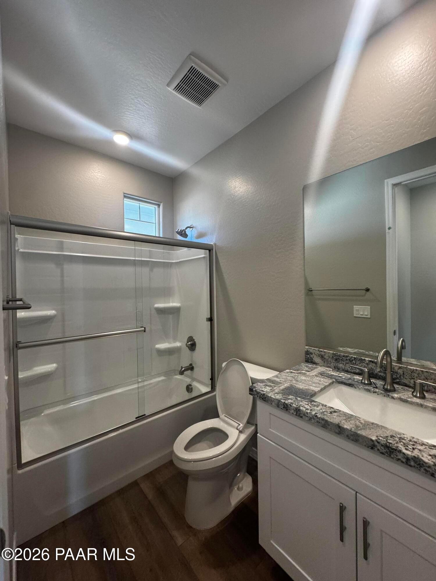 Modern master bathroom featuring glass shower-tub combo, double granite vanity, and wood floors in Davidson Homes Daybreak B, Prescott AZ