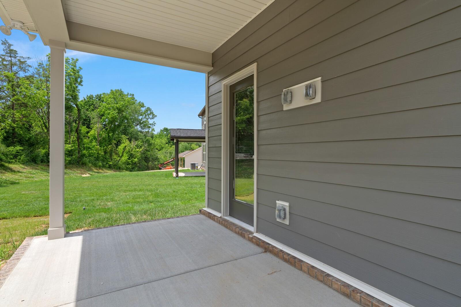 Covered back patio with gray siding and glass door at The Ridgeport C home in Woods Crossing, Gallatin, Tennessee.