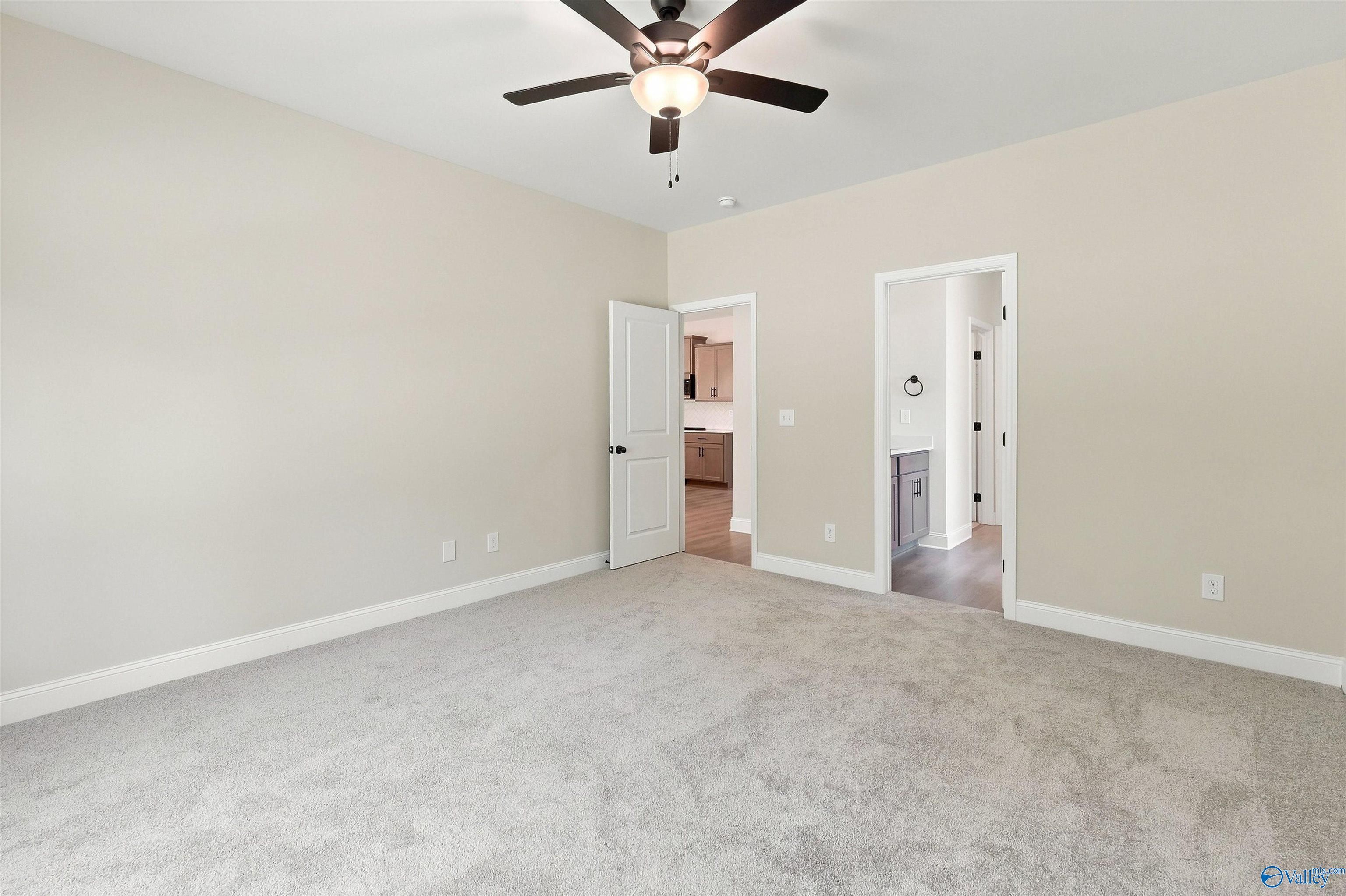 Spacious carpeted bedroom with ceiling fan in The Daphne floor plan by Davidson Homes in Spragins Cove, Huntsville, Alabama.