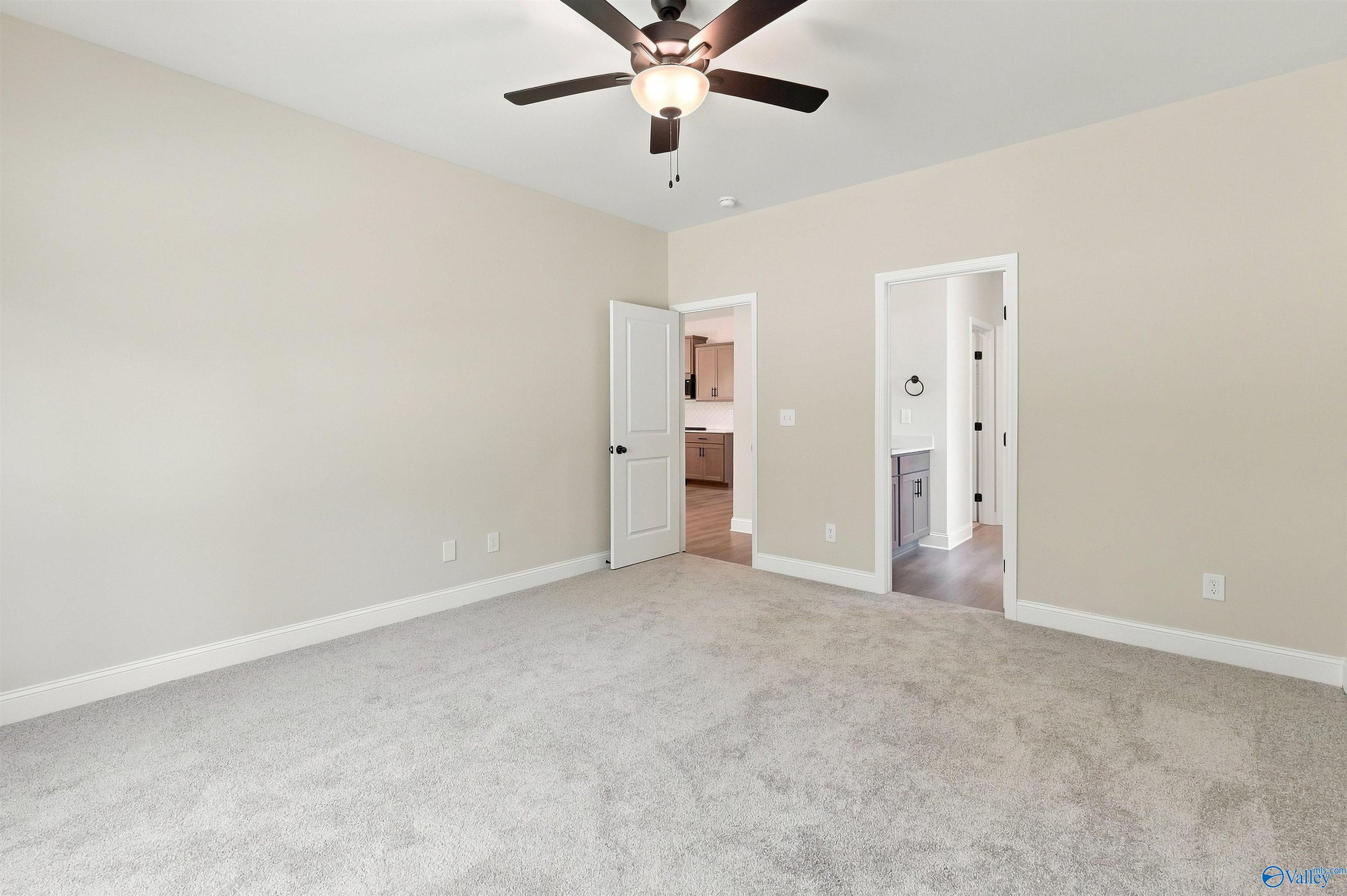 Spacious carpeted bedroom with ceiling fan in The Daphne floor plan by Davidson Homes in Spragins Cove, Huntsville, Alabama.