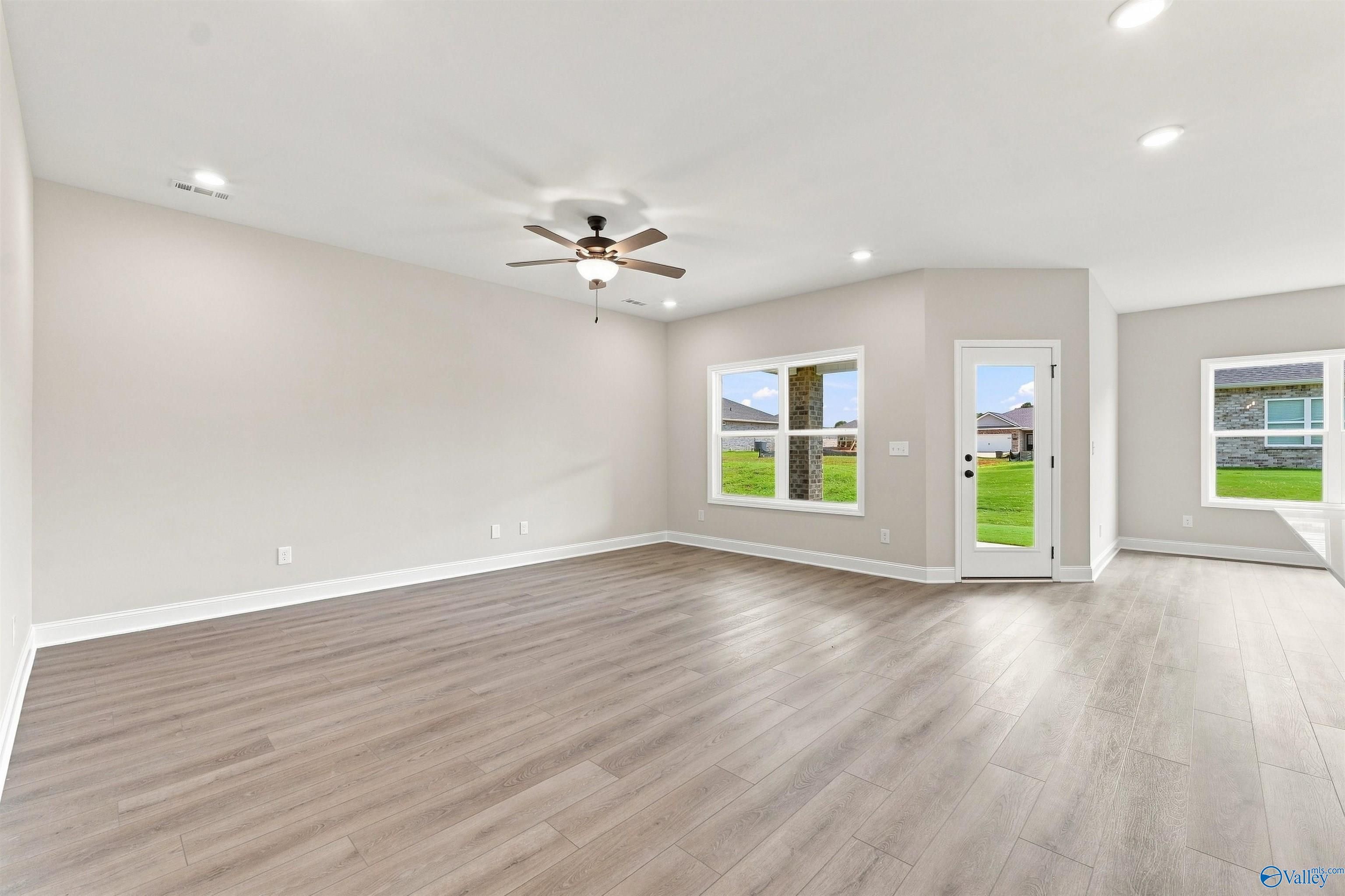 Bright open-concept living room with luxury vinyl plank floors and backyard access in Davidson Homes Everett B, Toney, Alabama